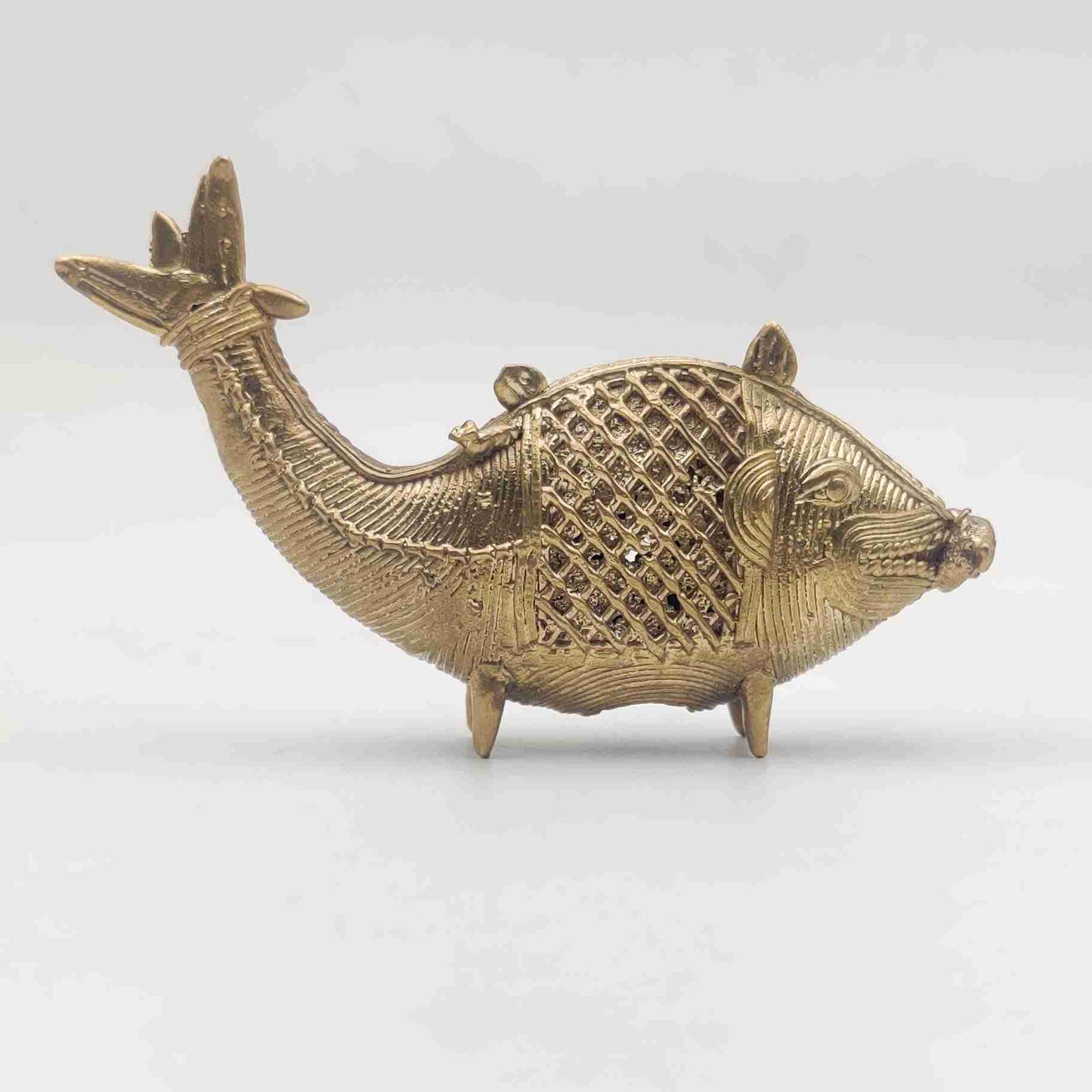 Miniature golden fish sculpture made using ancient Dhokra metal casting technique, representing abundance