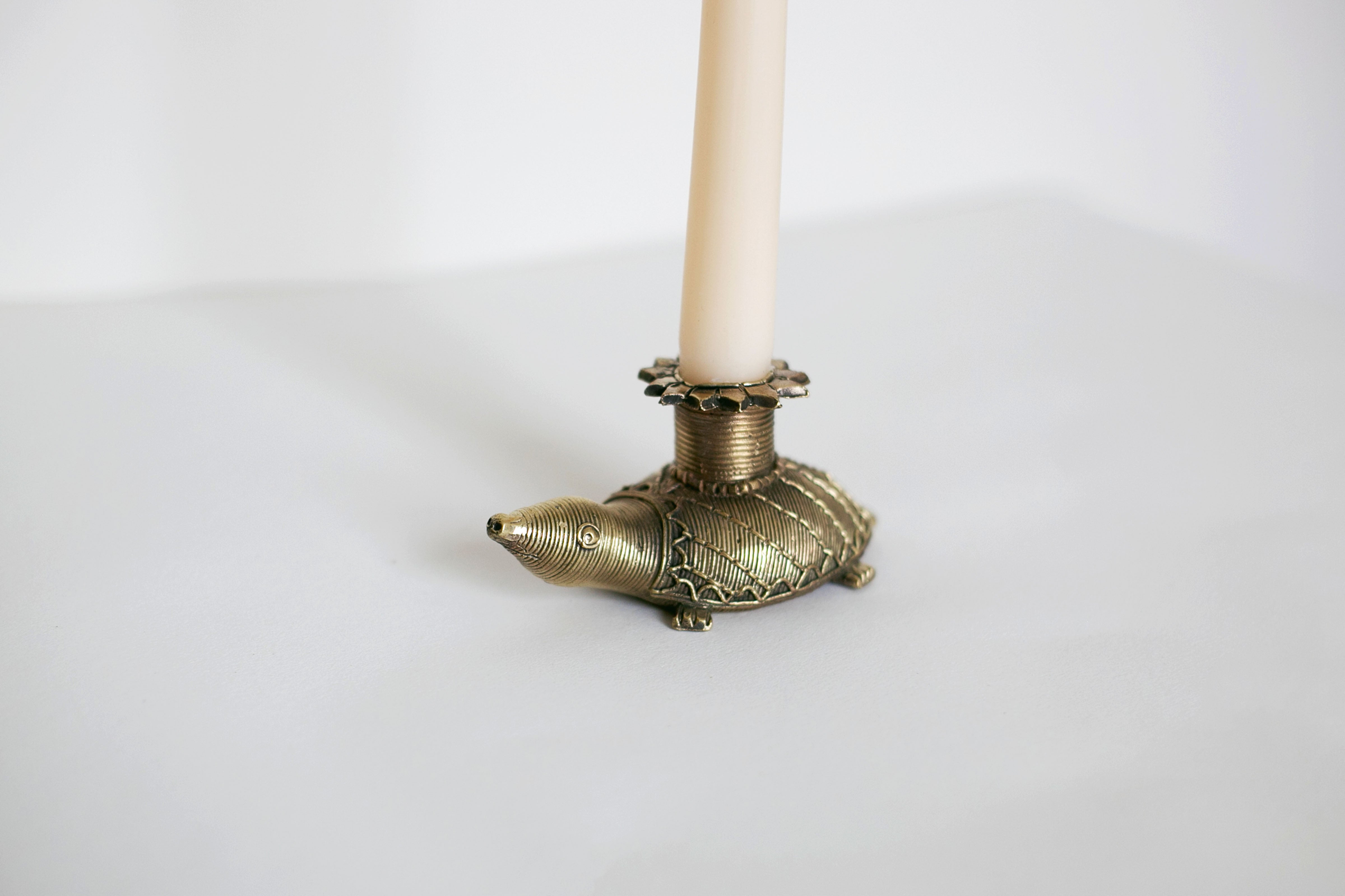 Brass turtle-shaped candle holder with white taper candle