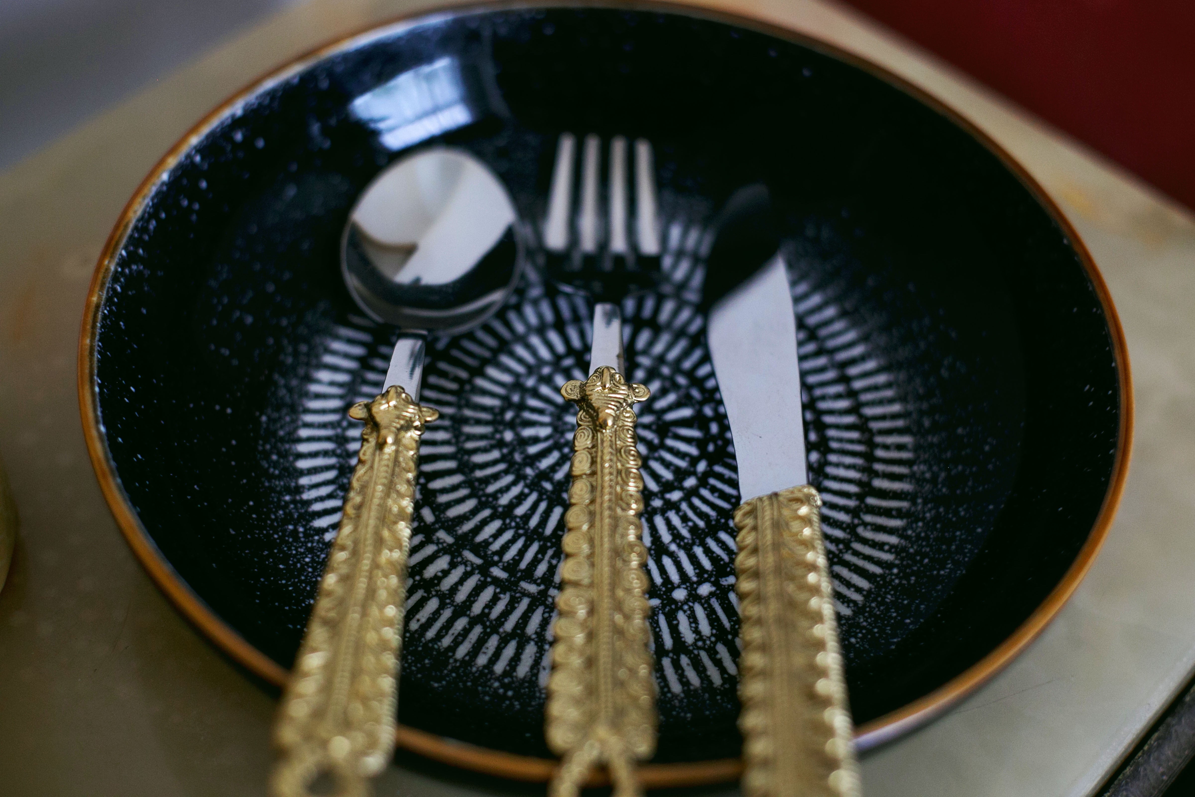 Dark ceramic plate with ornate gold-handled cutlery
