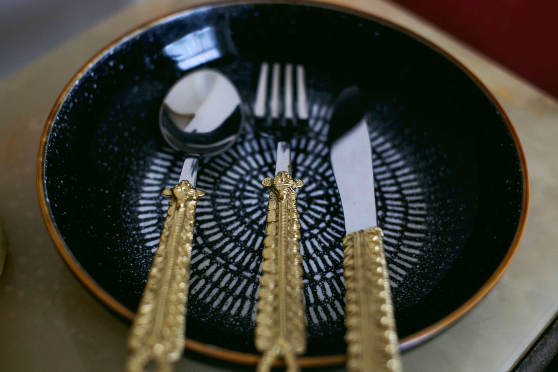 Dark ceramic plate with ornate gold-handled cutlery