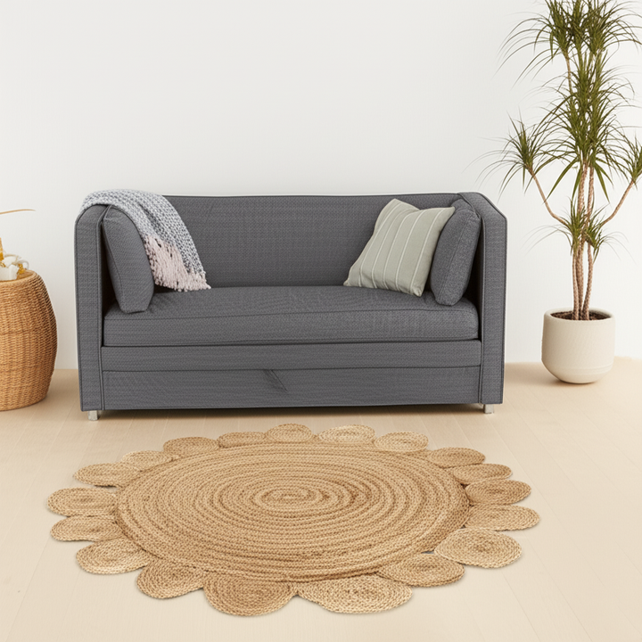 Round woven rug on a beige floor with a gray sofa and plant in the background