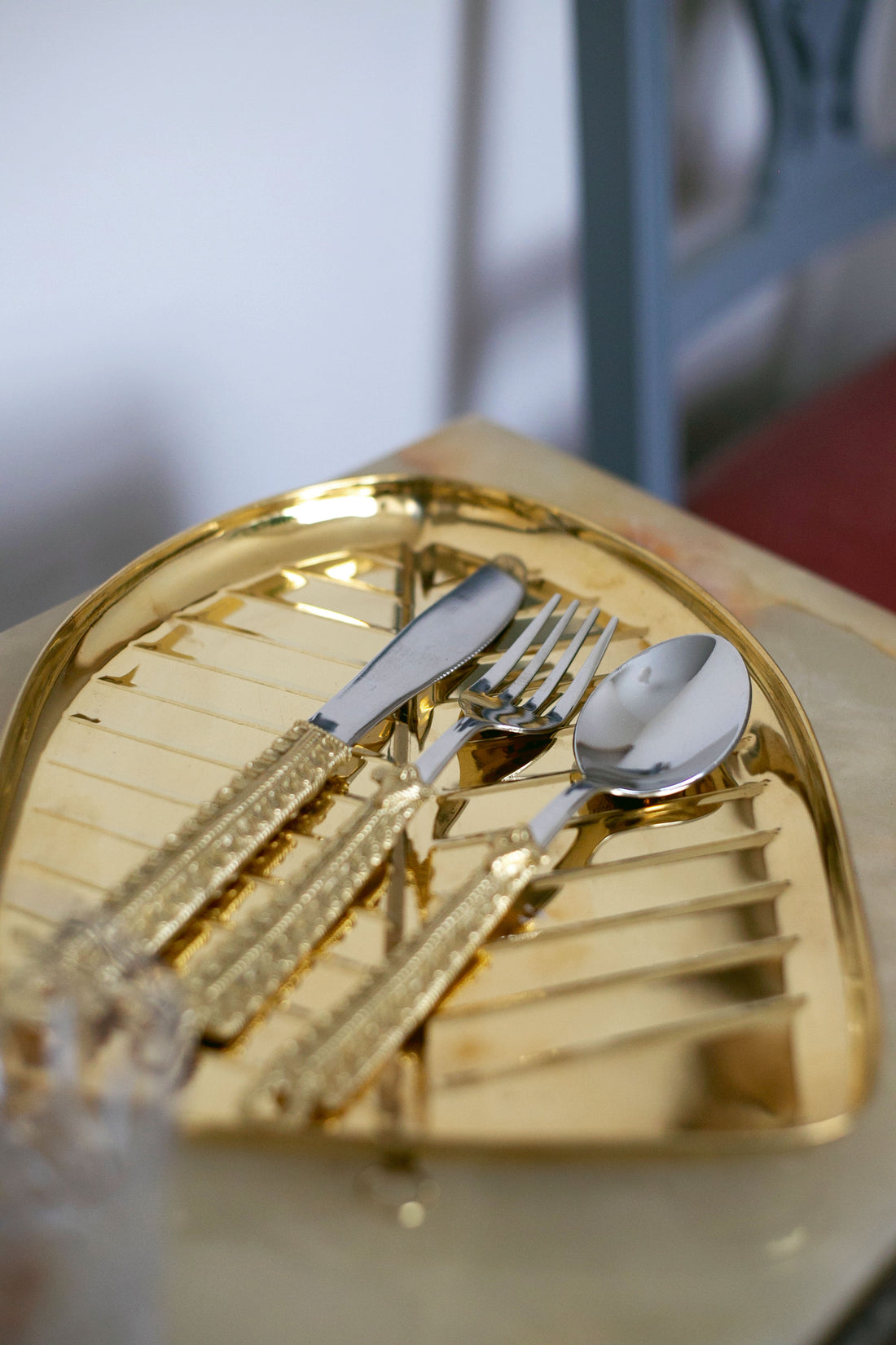 Golden tray with ornate knife, fork, and spoon featuring decorative handles.