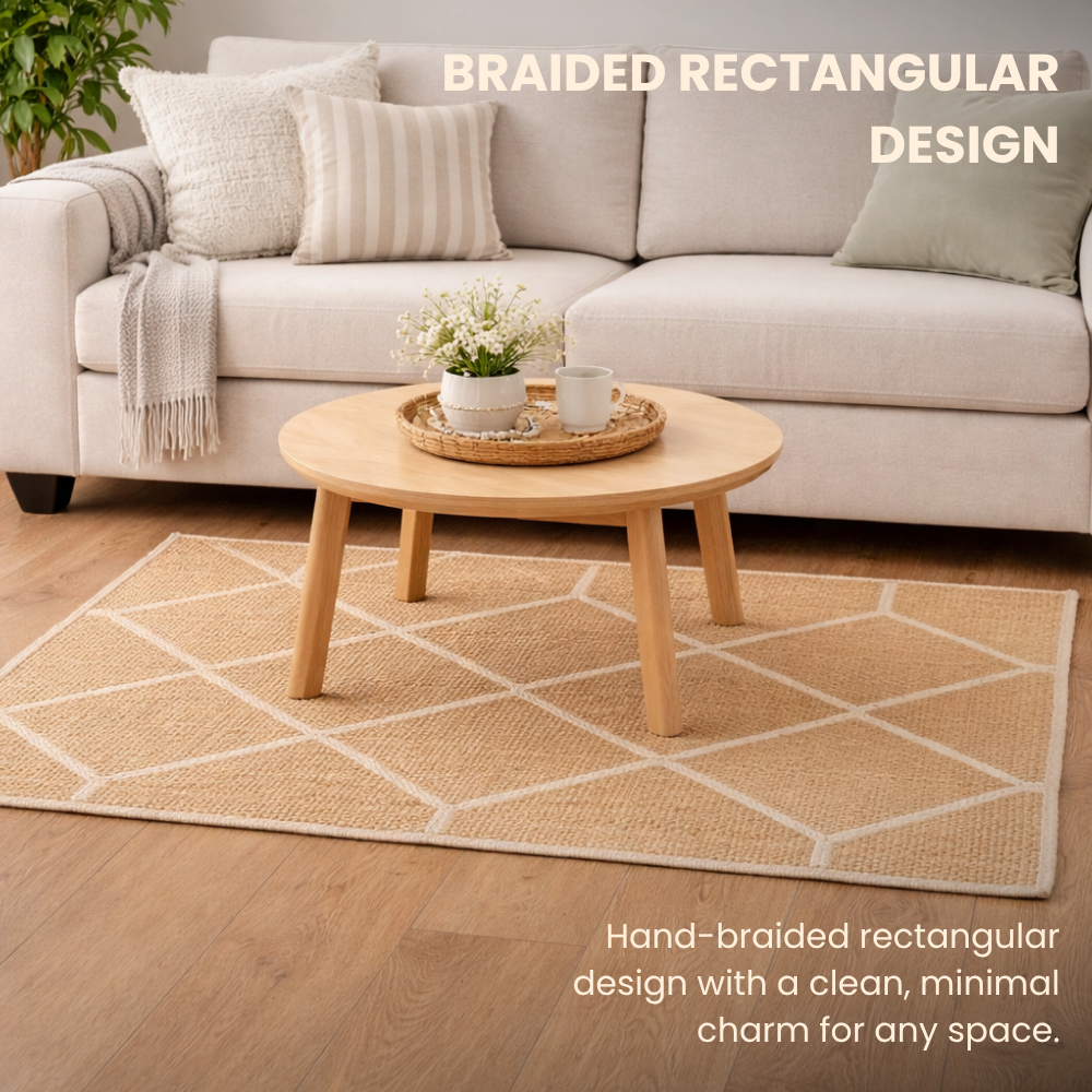 Living room with a beige sofa, round wooden table, and braided rectangular rug.