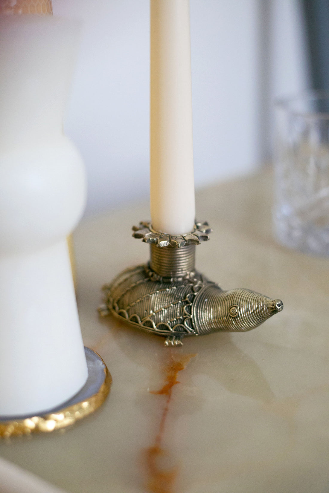 Close-up of ornate brass turtle holding a taper candle
