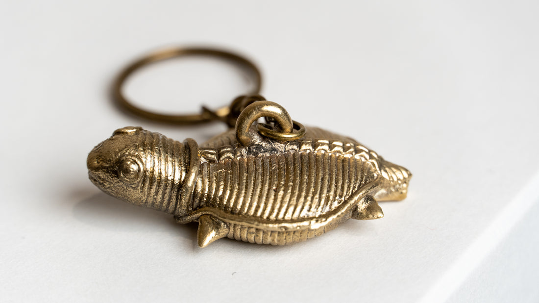Golden metallic turtle keychain with textured shell and limbs on a light surface