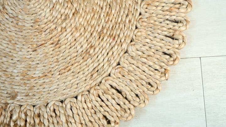 Woven natural fiber rug with tassels on a light tiled floor