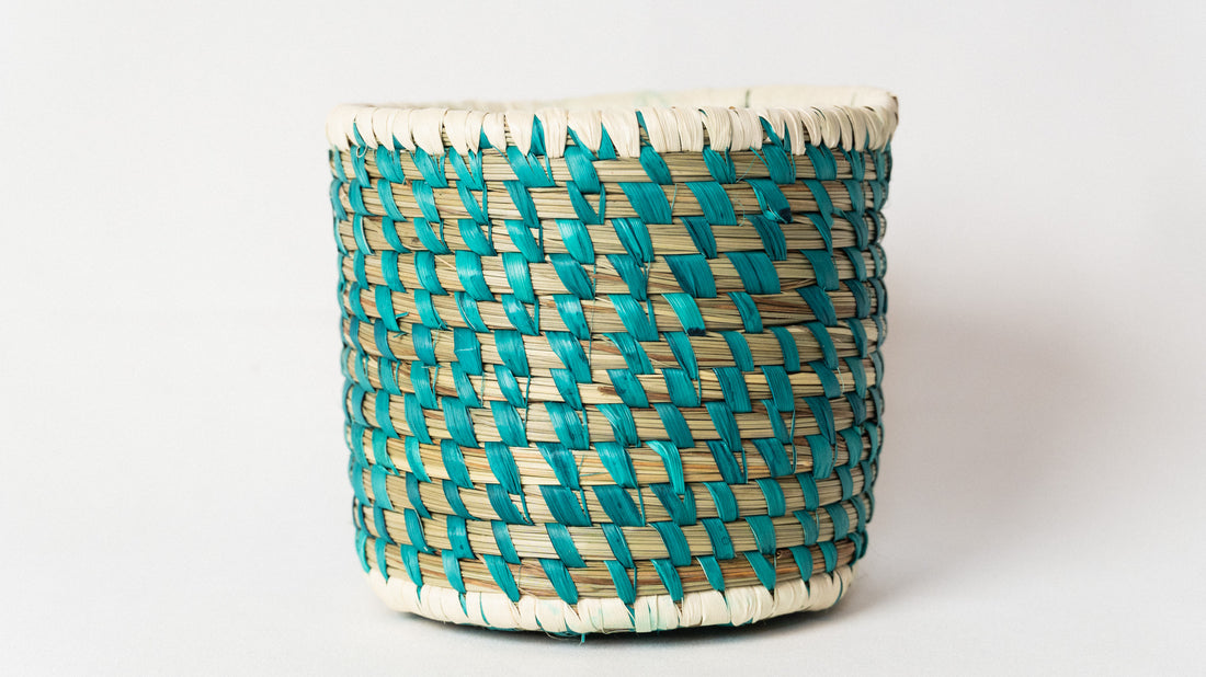 Woven basket with turquoise and beige pattern on a white background