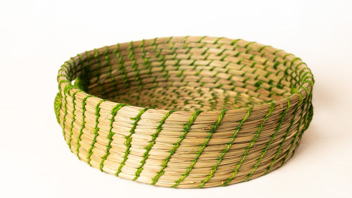Woven basket with green and beige pattern on a white background