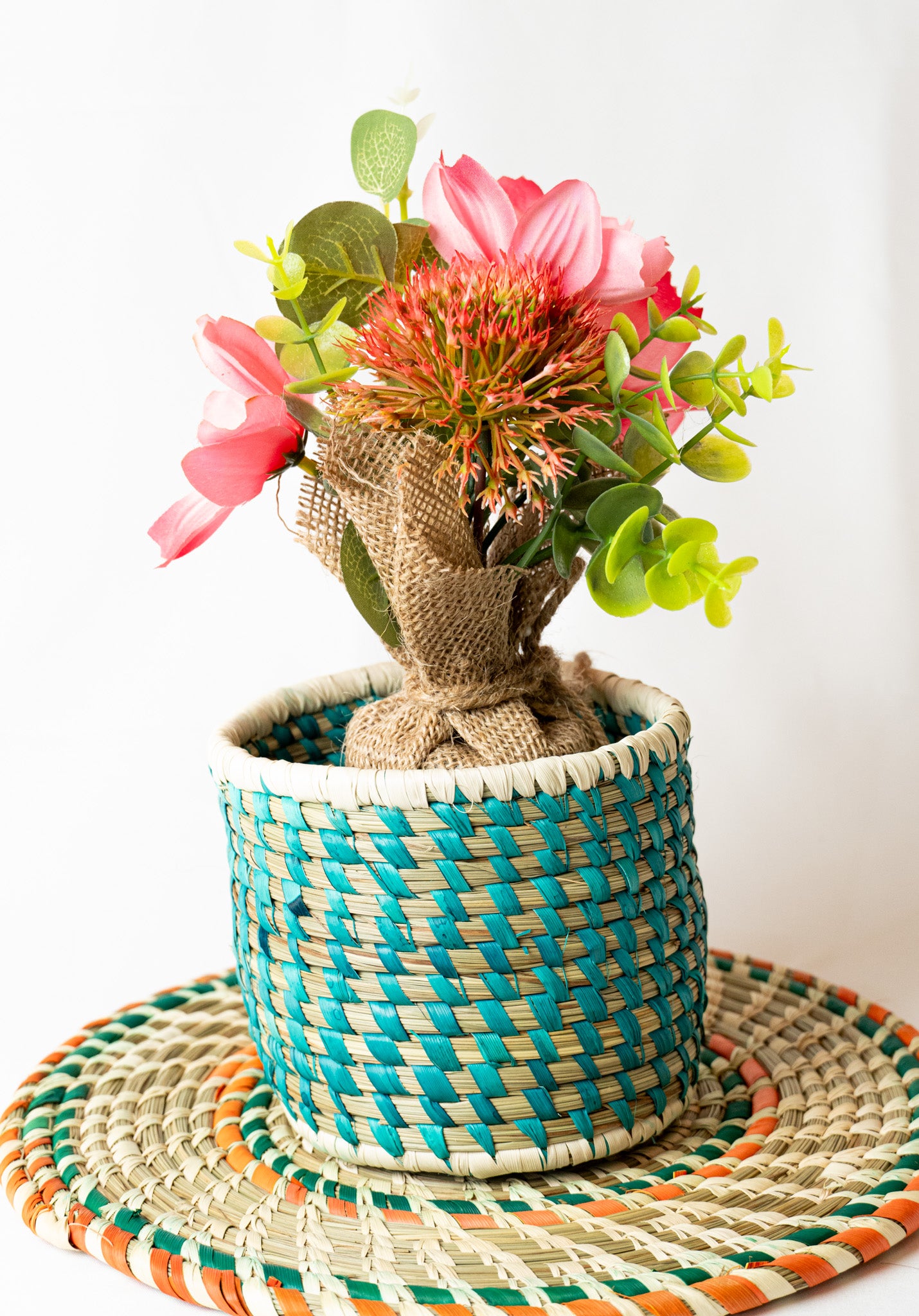 Decorative plant in a woven pot on a colorful mat with a white background