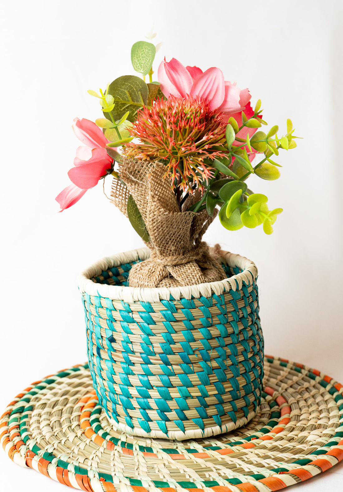 Decorative plant in a woven pot on a colorful mat with a white background