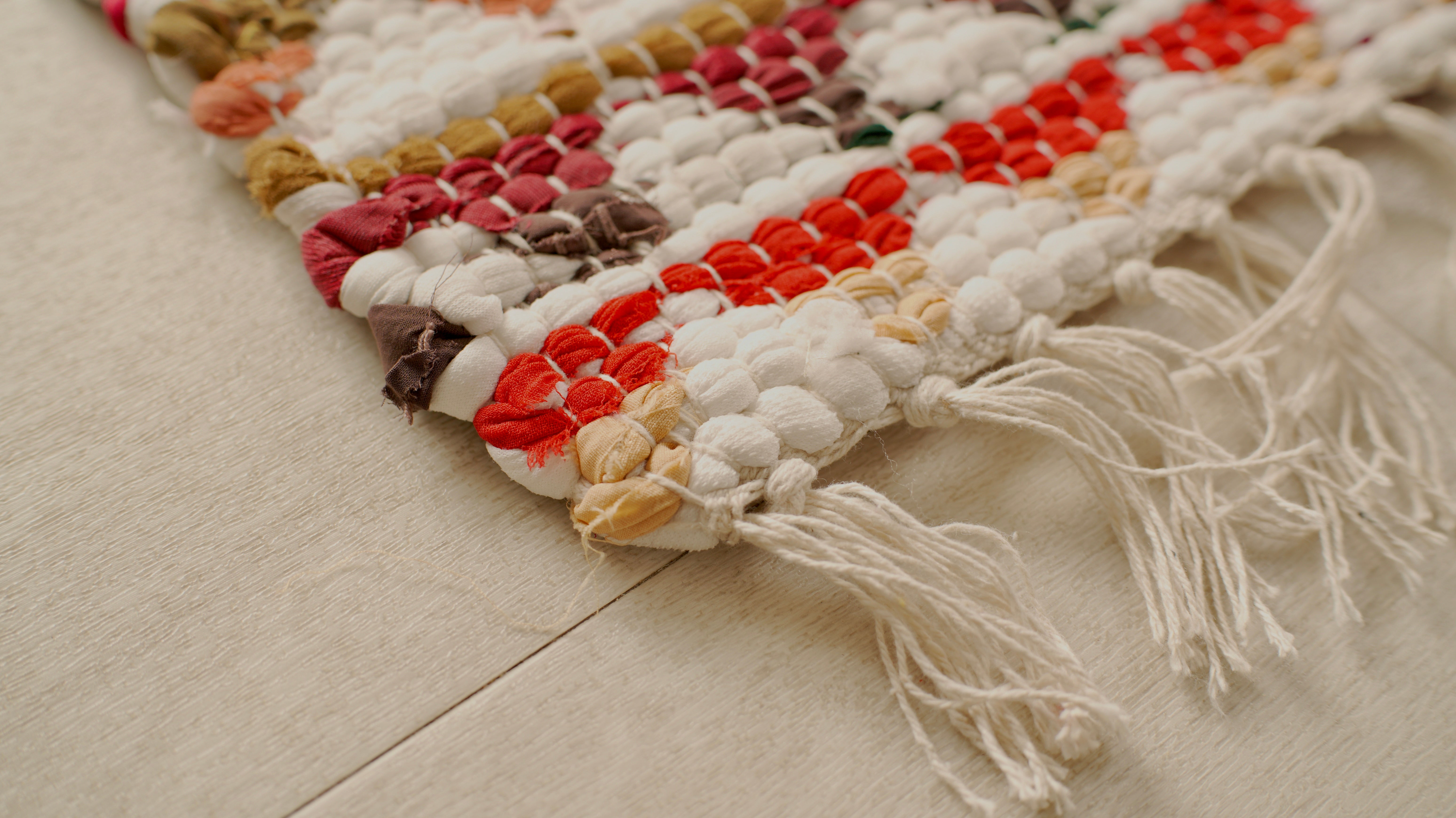 Colorful woven rug with tassels on a light wooden floor