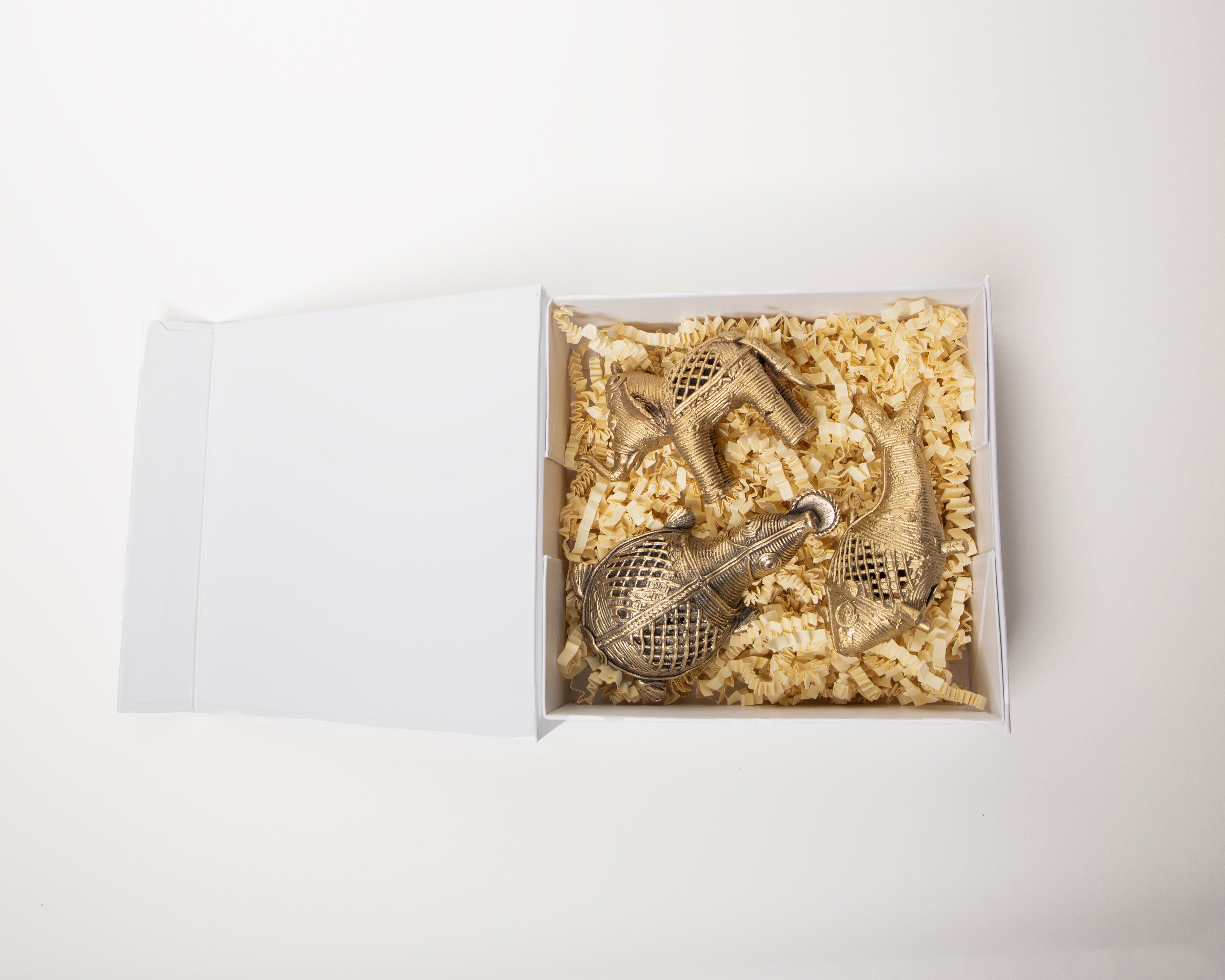 Open packaging showcasing ornate metallic animal-shaped ornaments on shredded paper