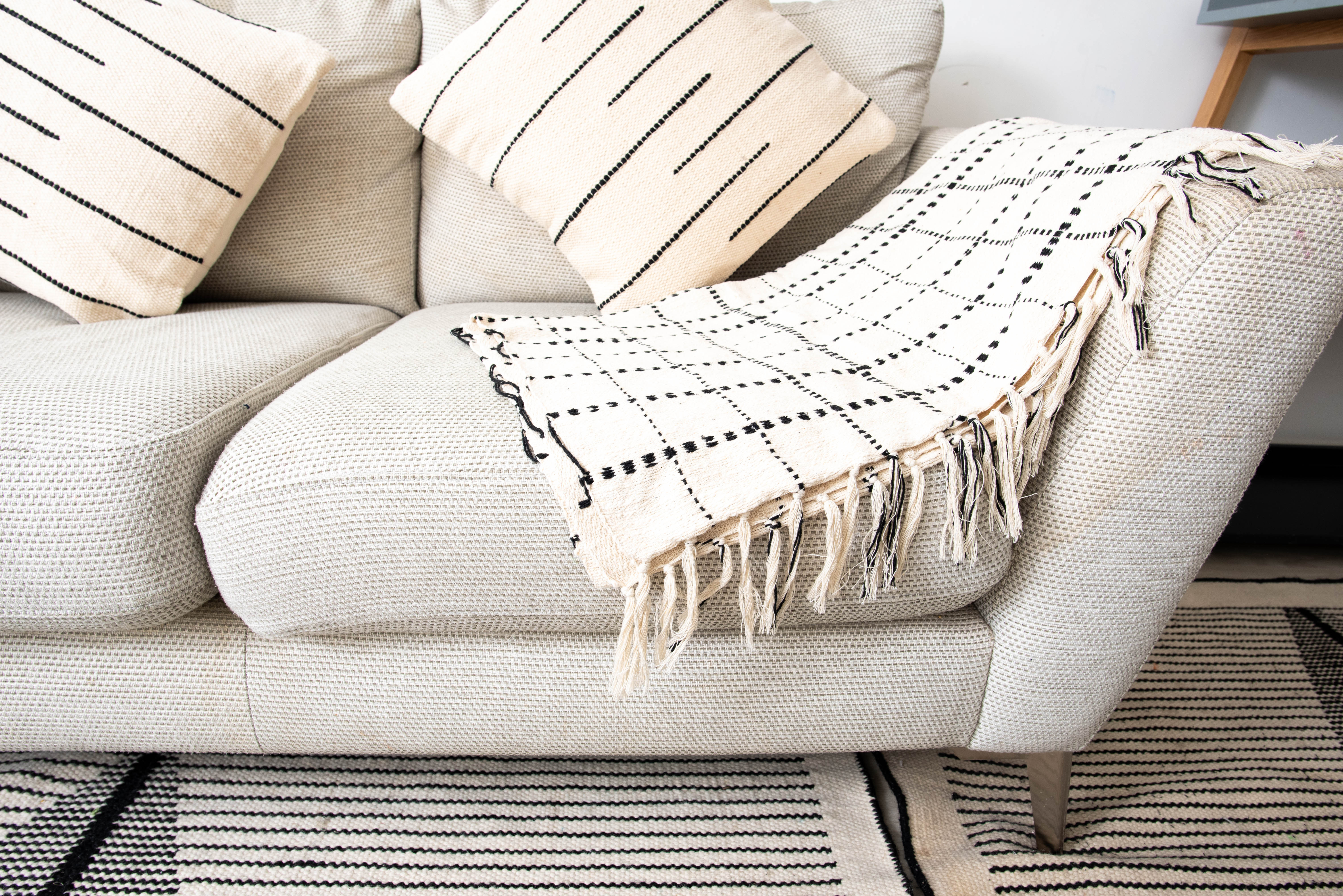 Light beige sofa with striped cushions and white color blanket