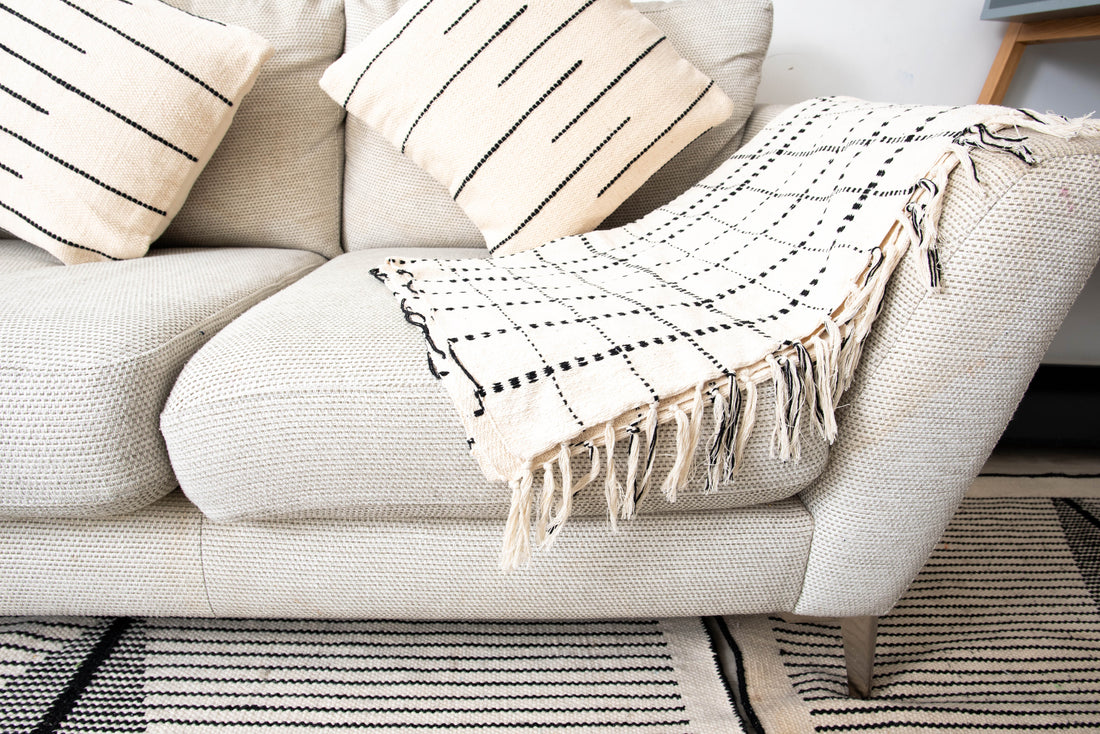 Light beige sofa with striped cushions and white color blanket