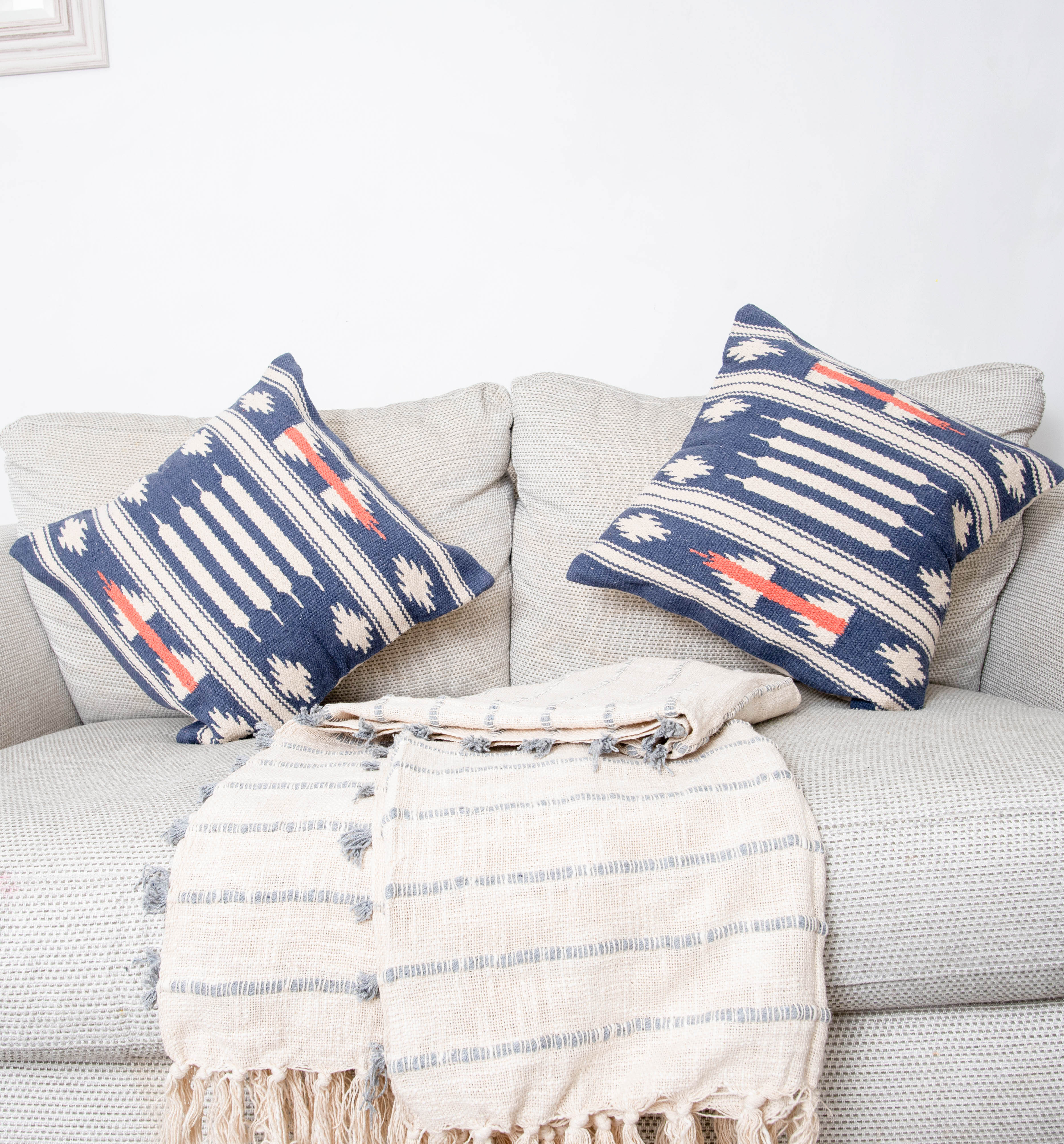Light gray sofa with patterned pillows and striped throw.