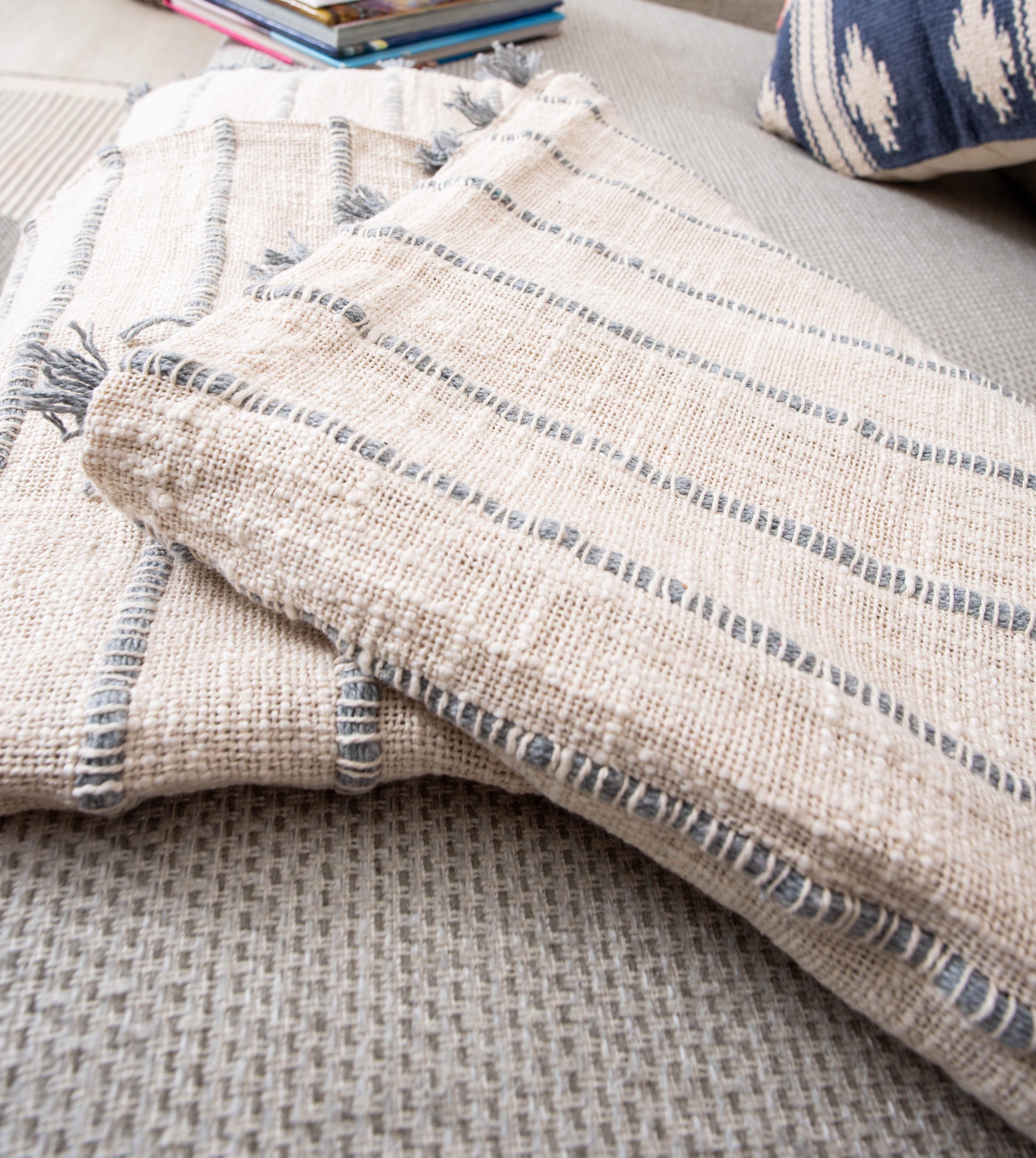Two beige striped blankets with books and pillow.