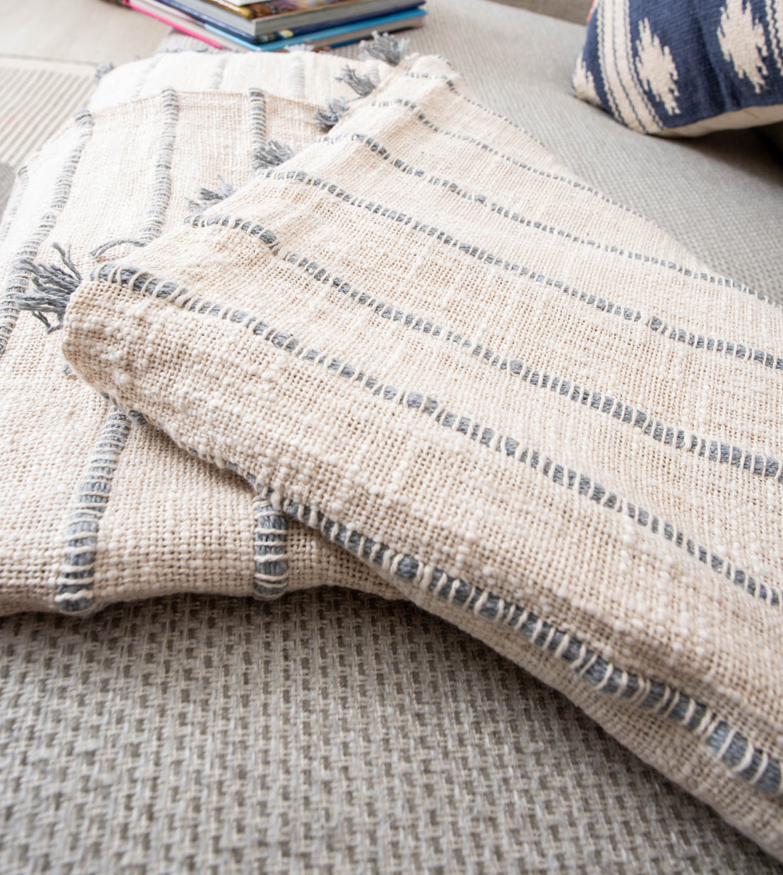 Two beige striped blankets with books and pillow.