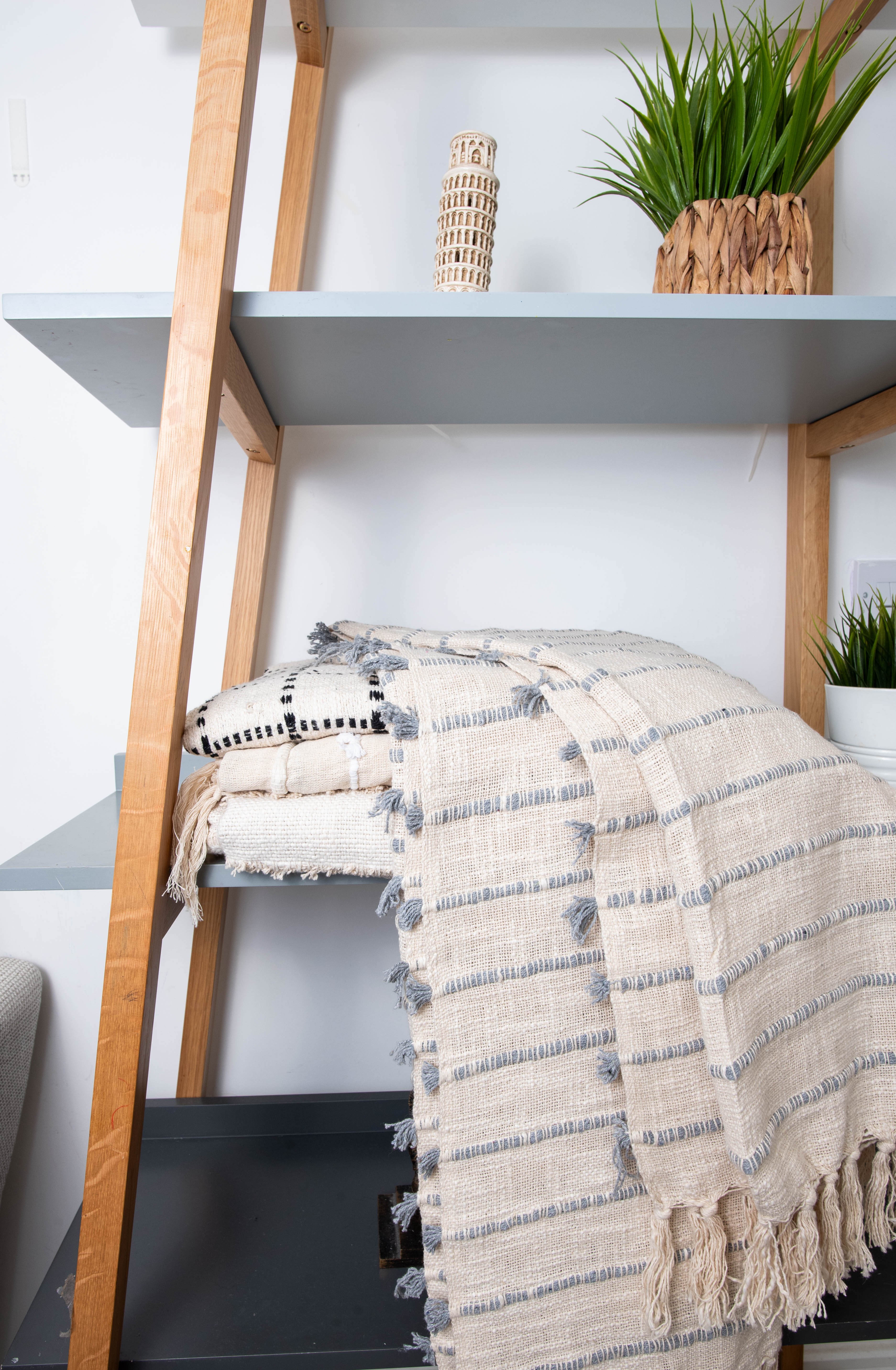 Folded striped blankets on shelf with plants.