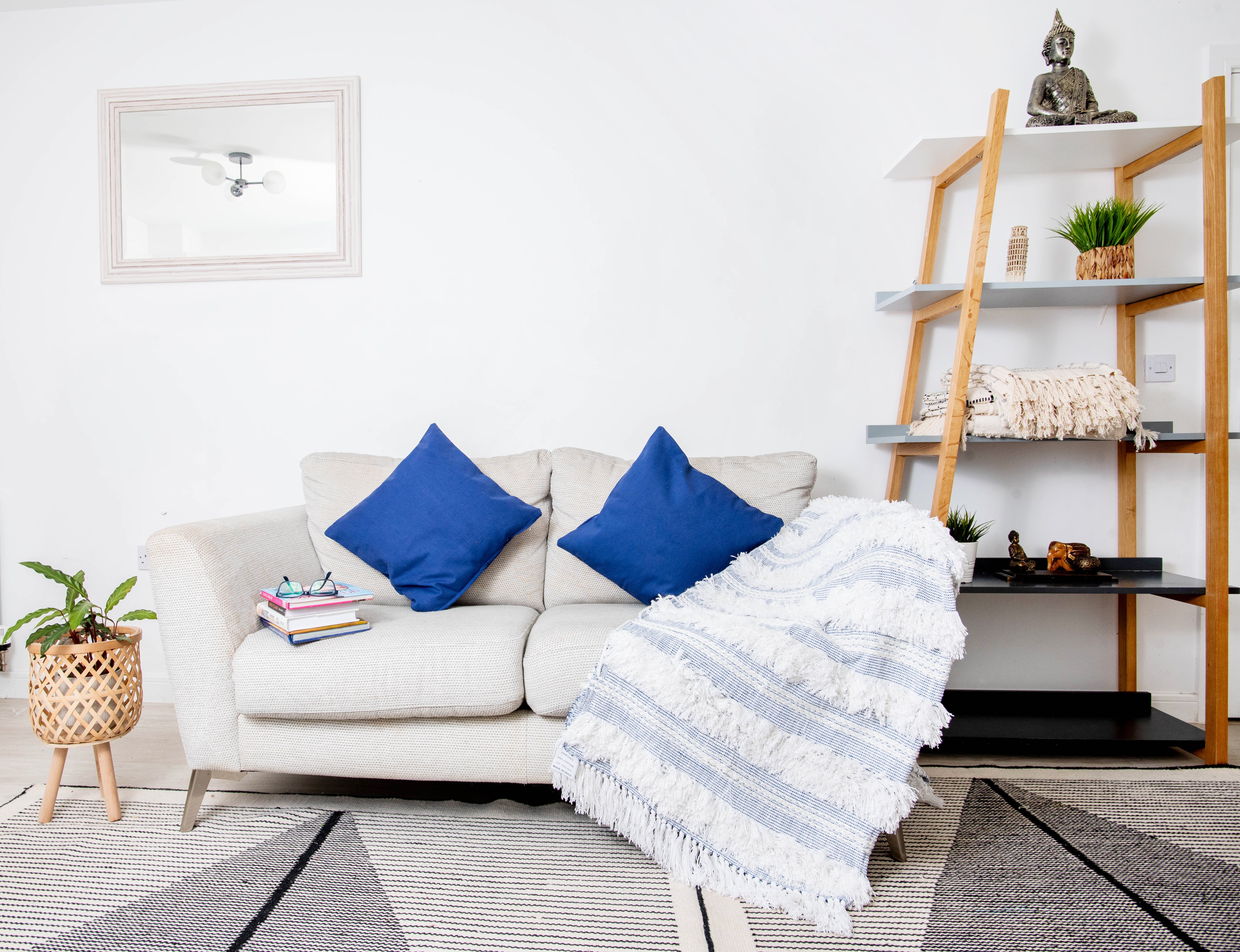 This image features a decorative throw blanket and throw pillows styled on a modern sofa. 