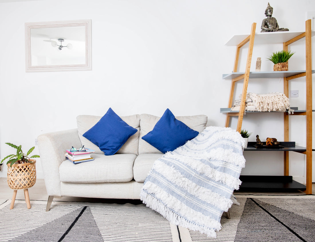 This image features a decorative throw blanket and throw pillows styled on a modern sofa. 
