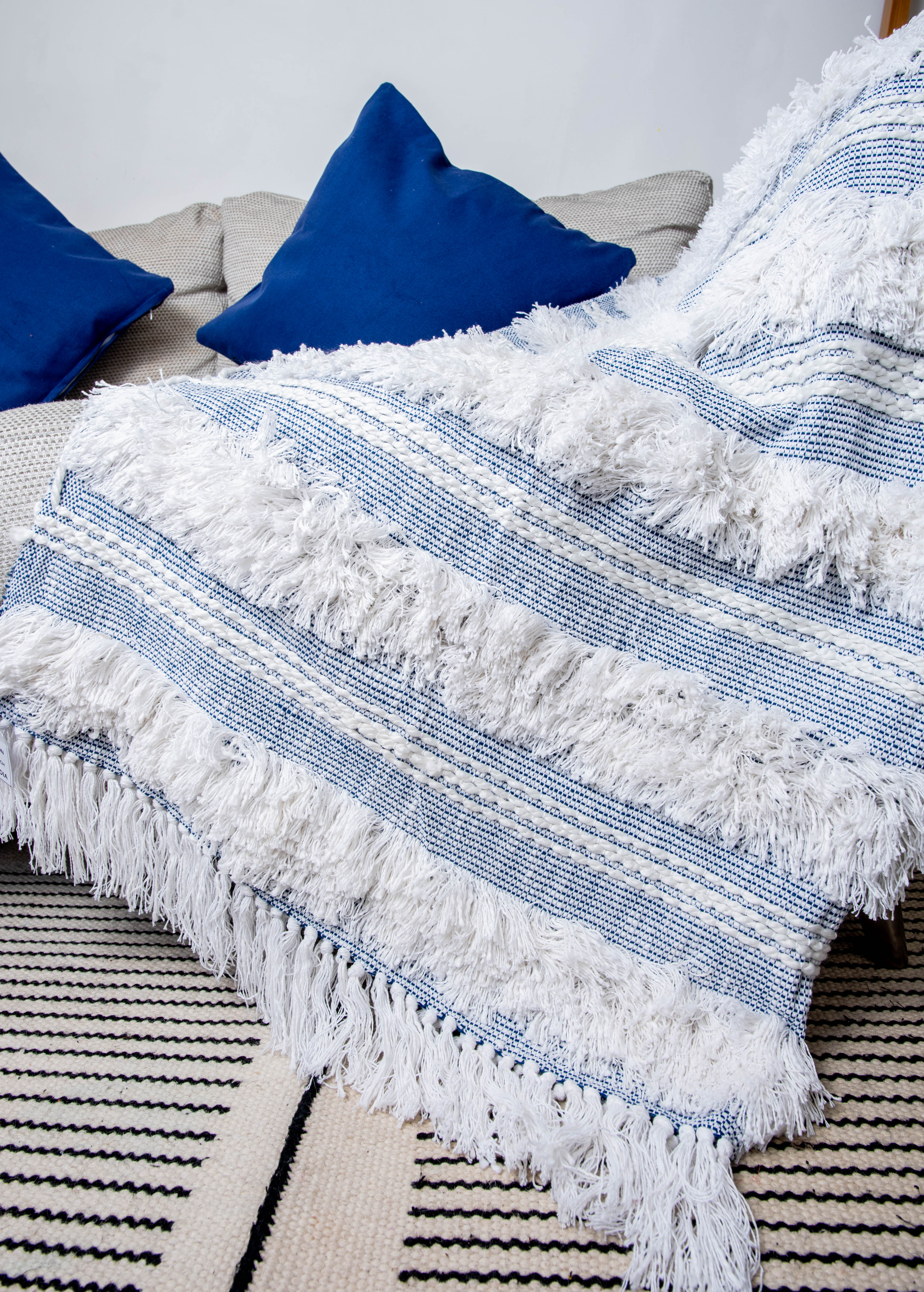 This blue and white tufted throw blanket is handcrafted from 100% natural cotton. 