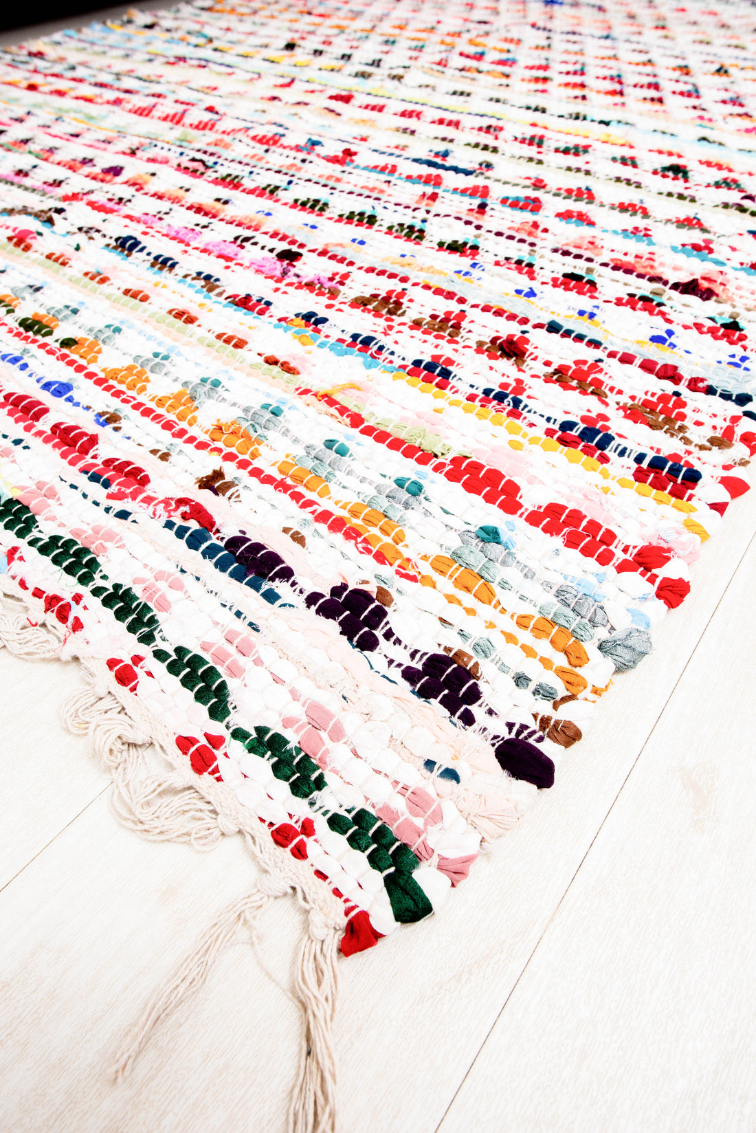 This item is a handcrafted multicolor Chindi rag rug made from woven cotton rags. 