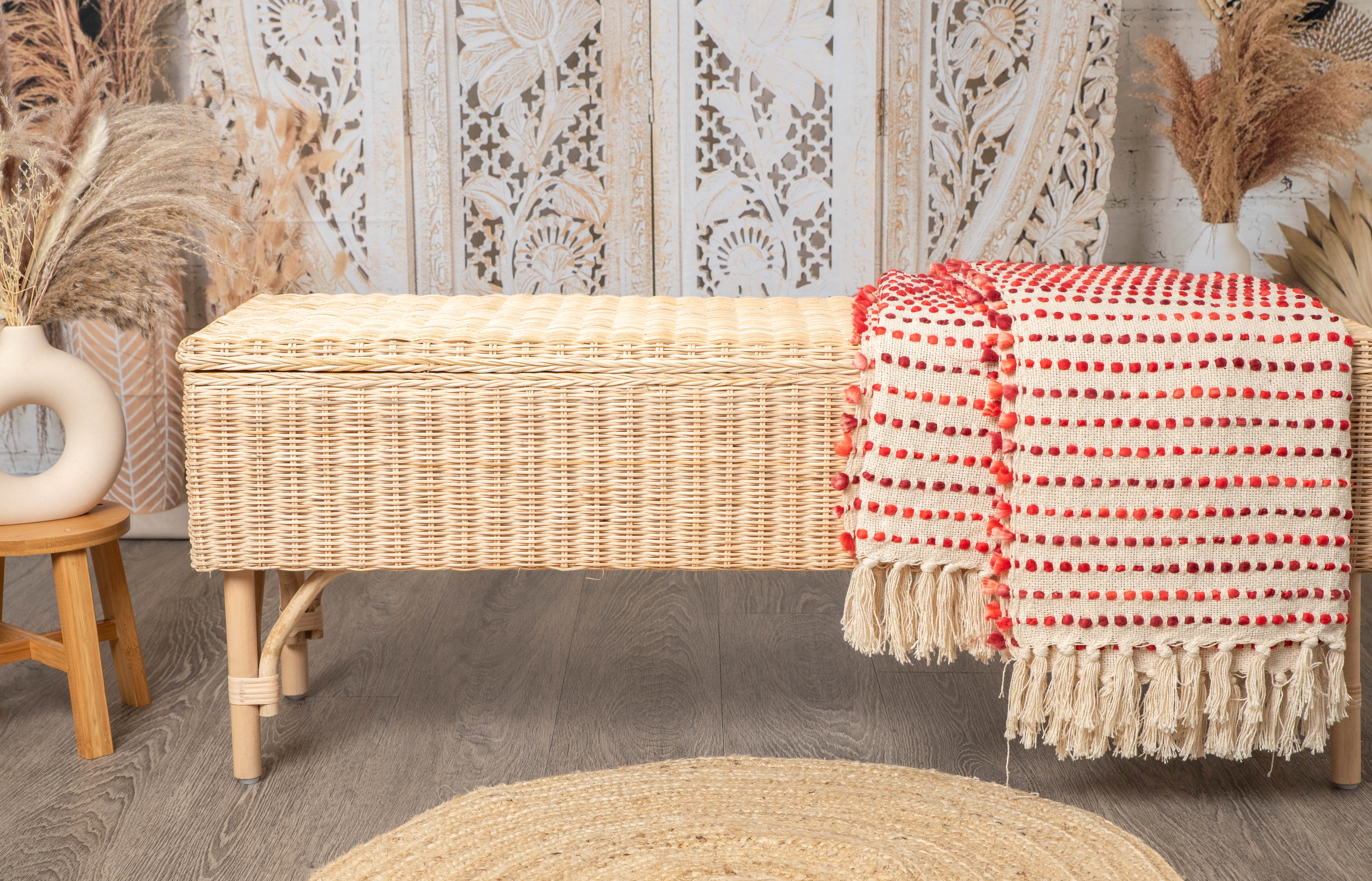Bohemian wicker bench with cream throw and woven rug in cozy interior