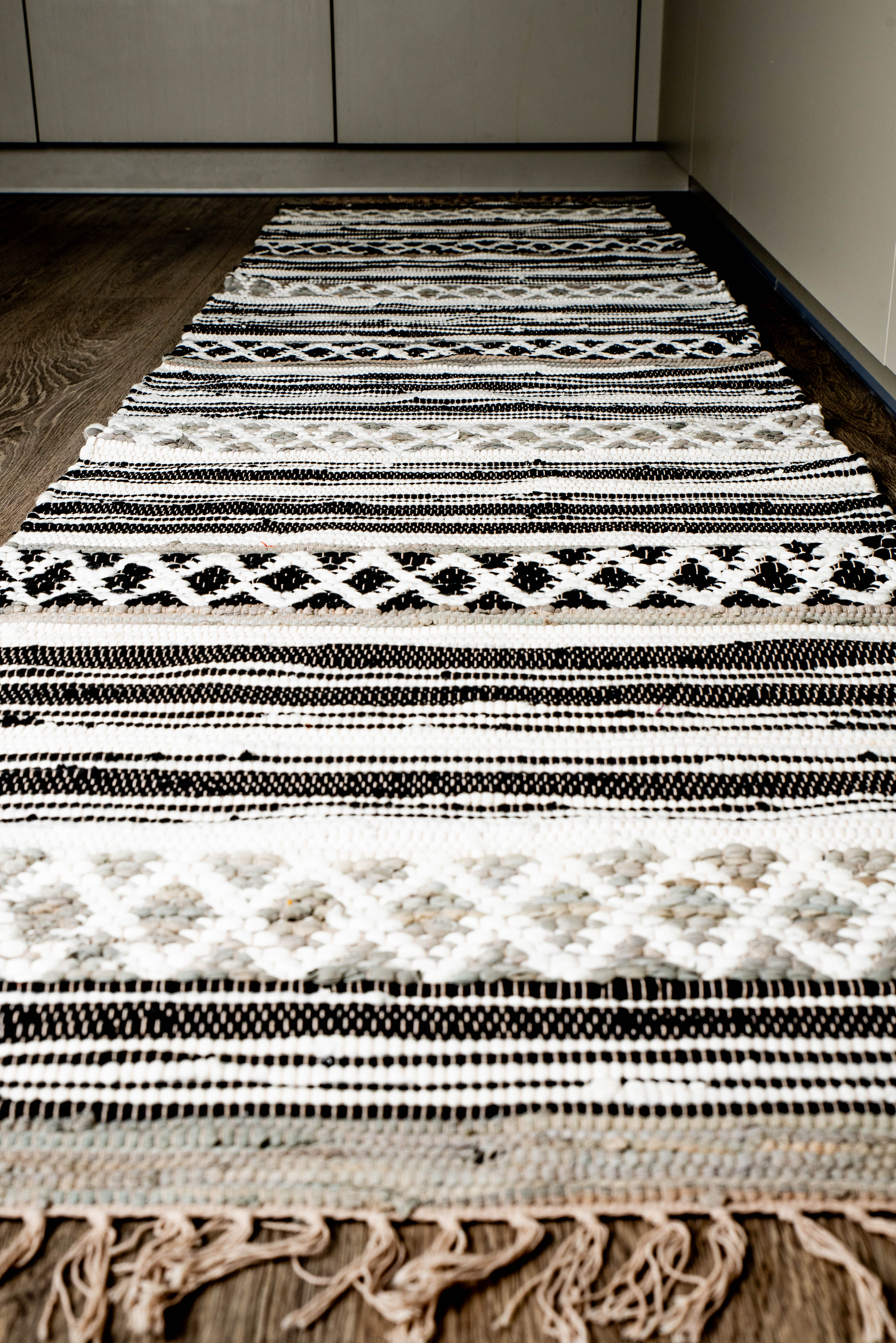 Handwoven rug with black, white, and beige geometric diamond and zigzag patterns