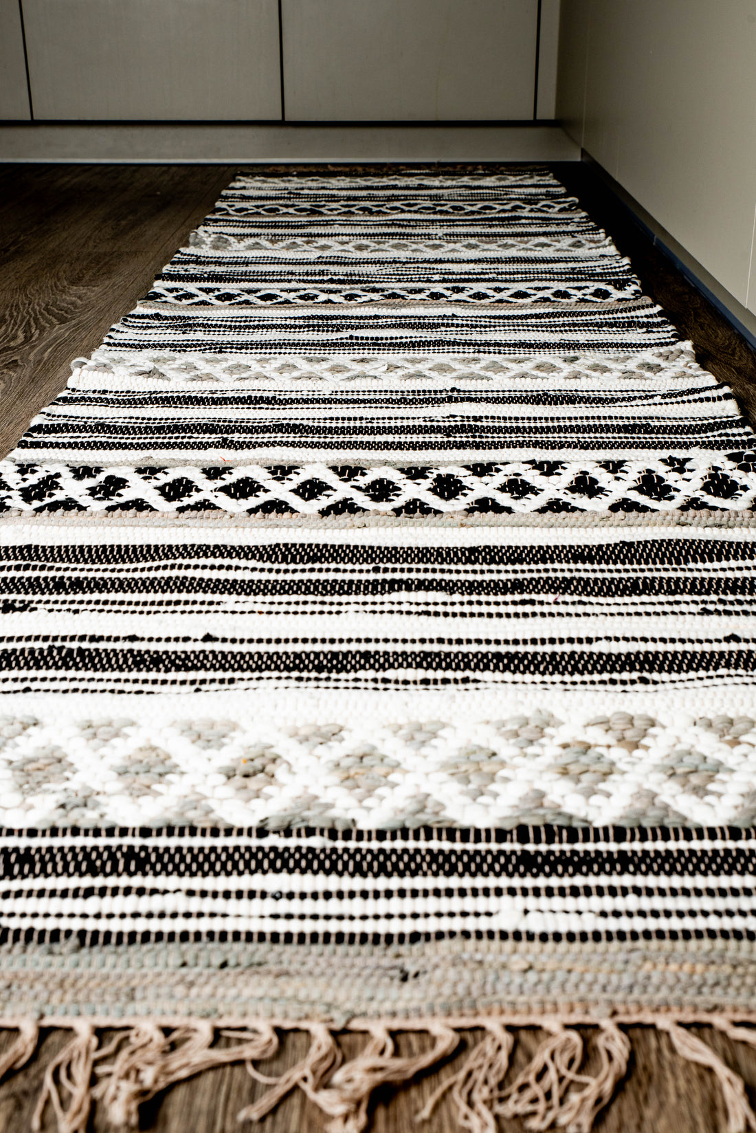 Handwoven rug with black, white, and beige geometric diamond and zigzag patterns