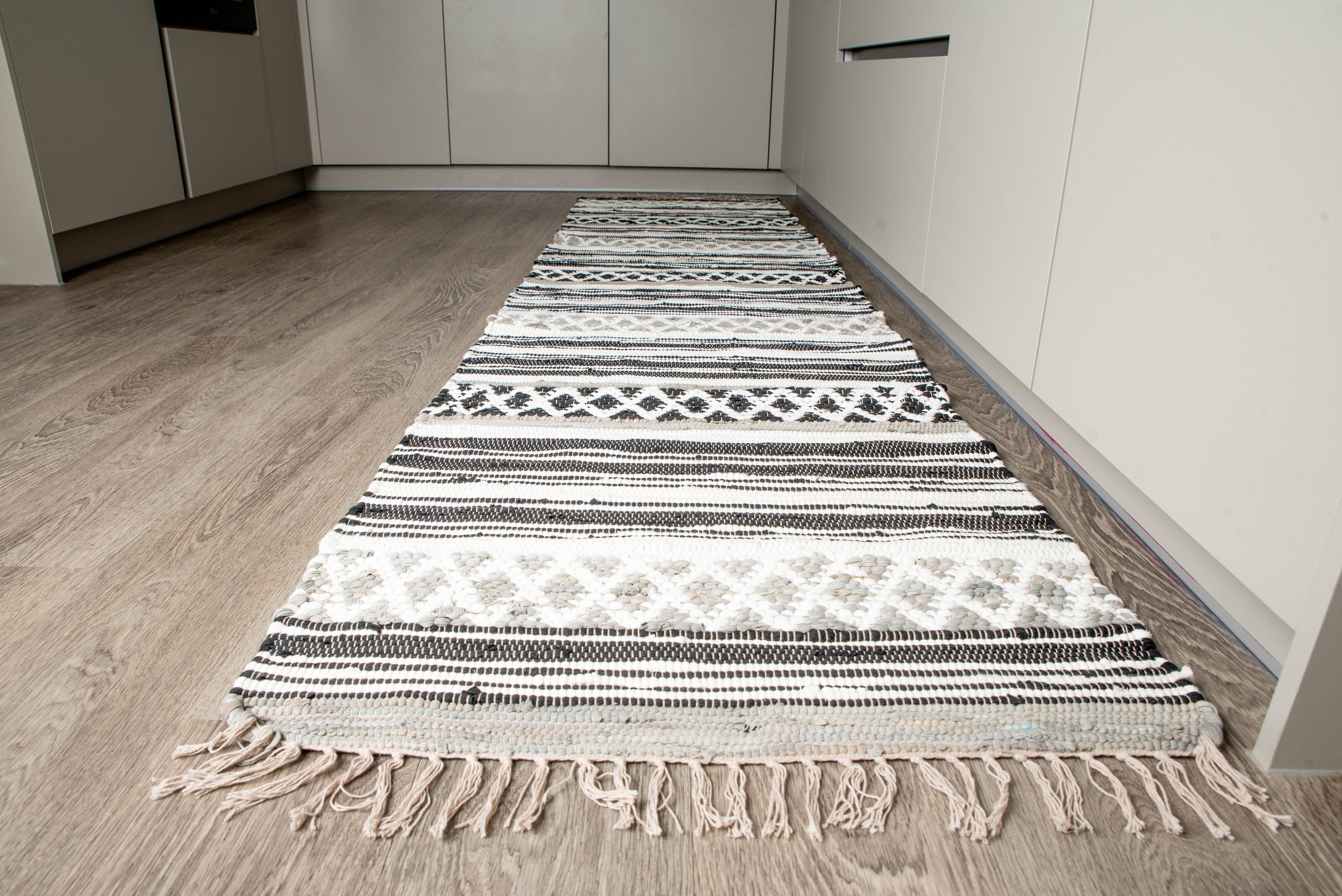 Decorative geometric rug with alternating stripes and motifs styled in minimalist kitchen interior