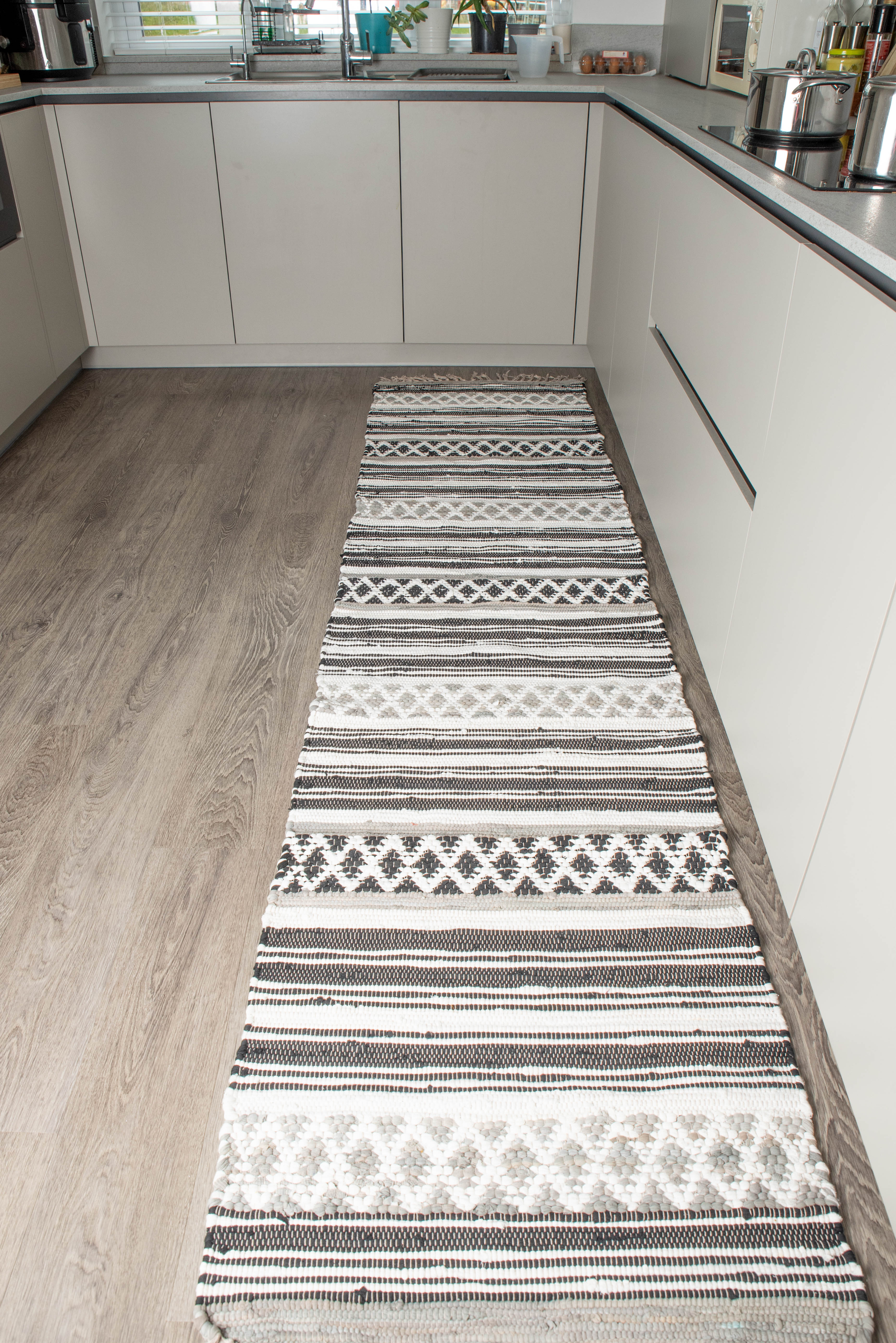 Long patterned runner rug placed between kitchen cabinets