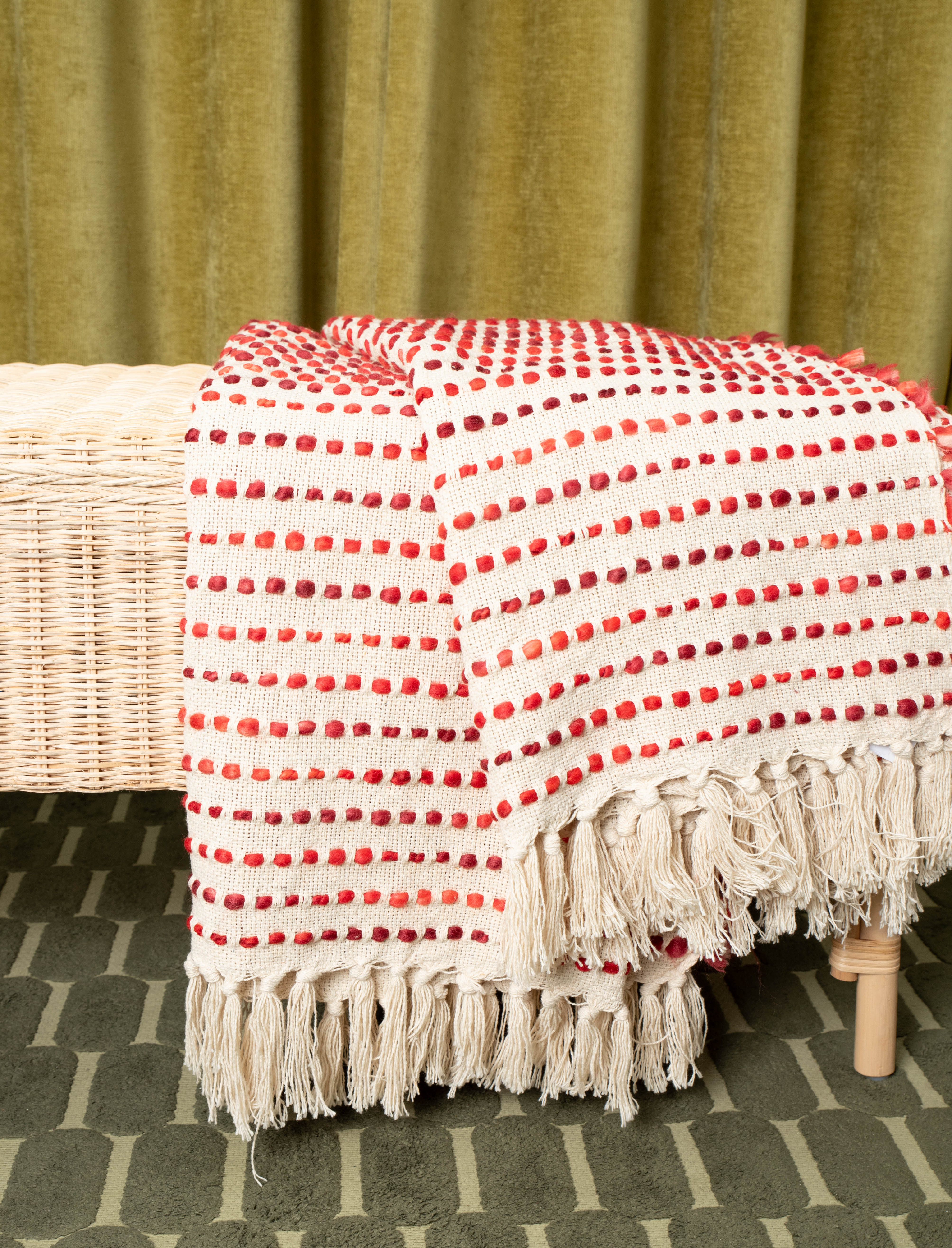 Decorative woven cloth in warm tones styled with bench and patterned rug
