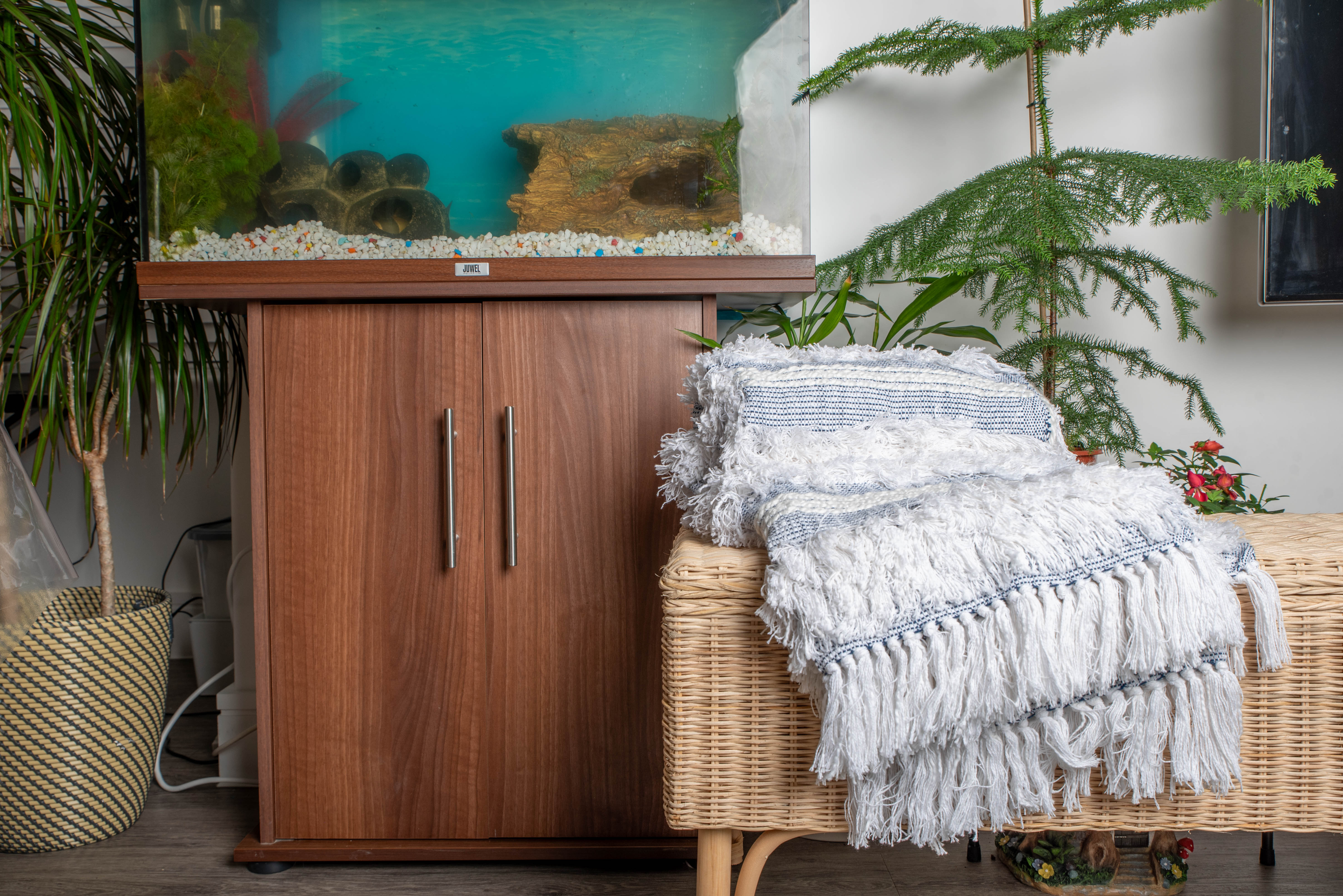 Blue and white woven throw blankets with fringe on wicker bench