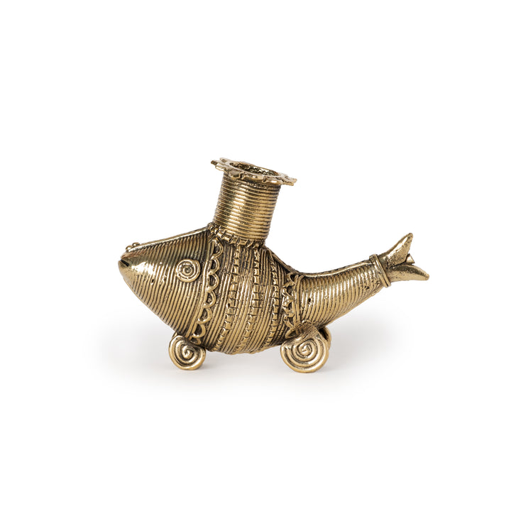 A gold-colored metal candle holder in the shape of a fish with a decorative pattern.