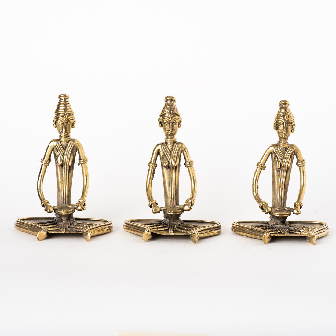 These items are handcrafted Dhokra art brass metal figurines depicting sitting women musicians playing percussion instruments. 