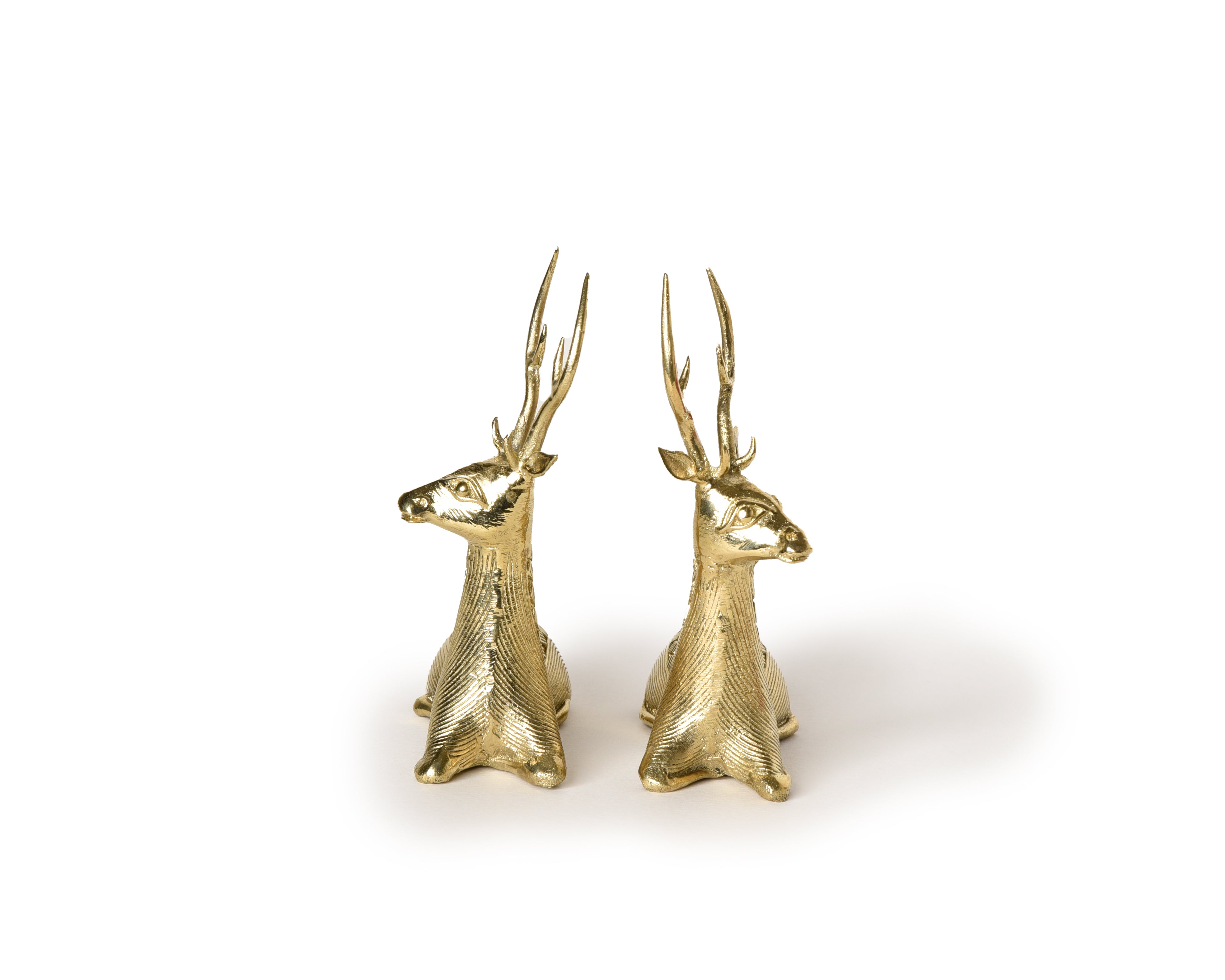 A pair of handmade brass sitting deer sculptures with detailed depiction of the deer's muscular form and serene expressions.