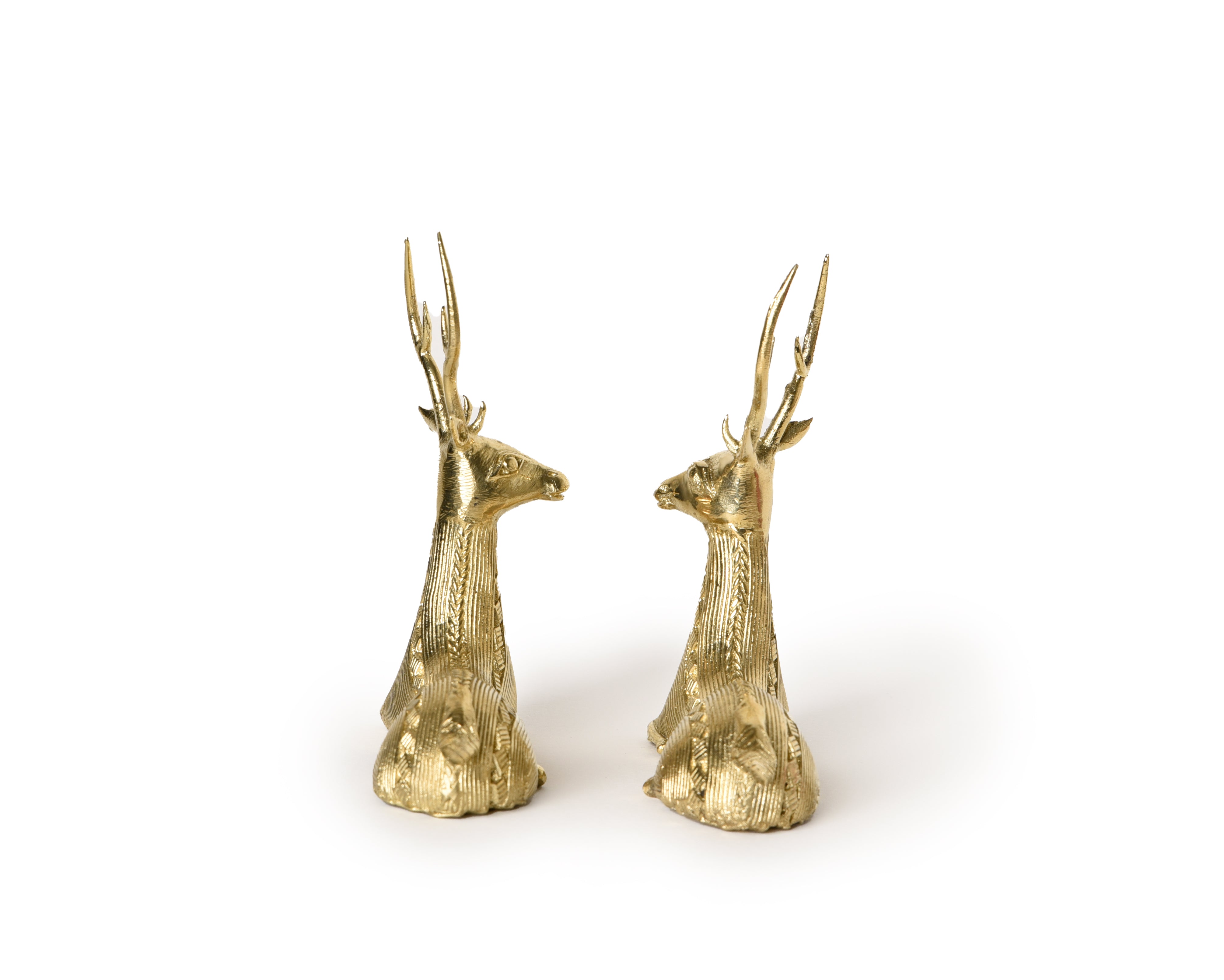 A pair of handmade brass sitting deer sculptures with detailed depiction of the deer's muscular form and serene expressions.