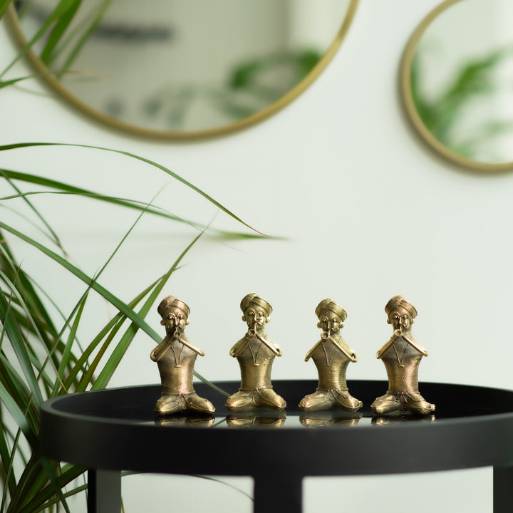 Four brass metal sculptures of sitting men musicians