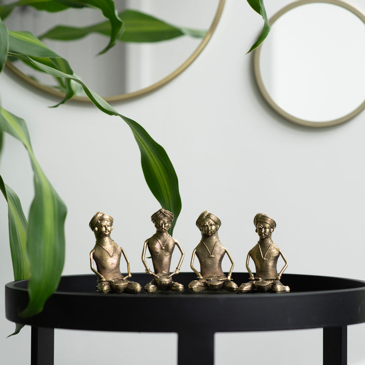 Four brass metal sculptures of sitting men musicians