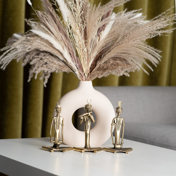 A gold-finished metal statue of three sitting men musicians.