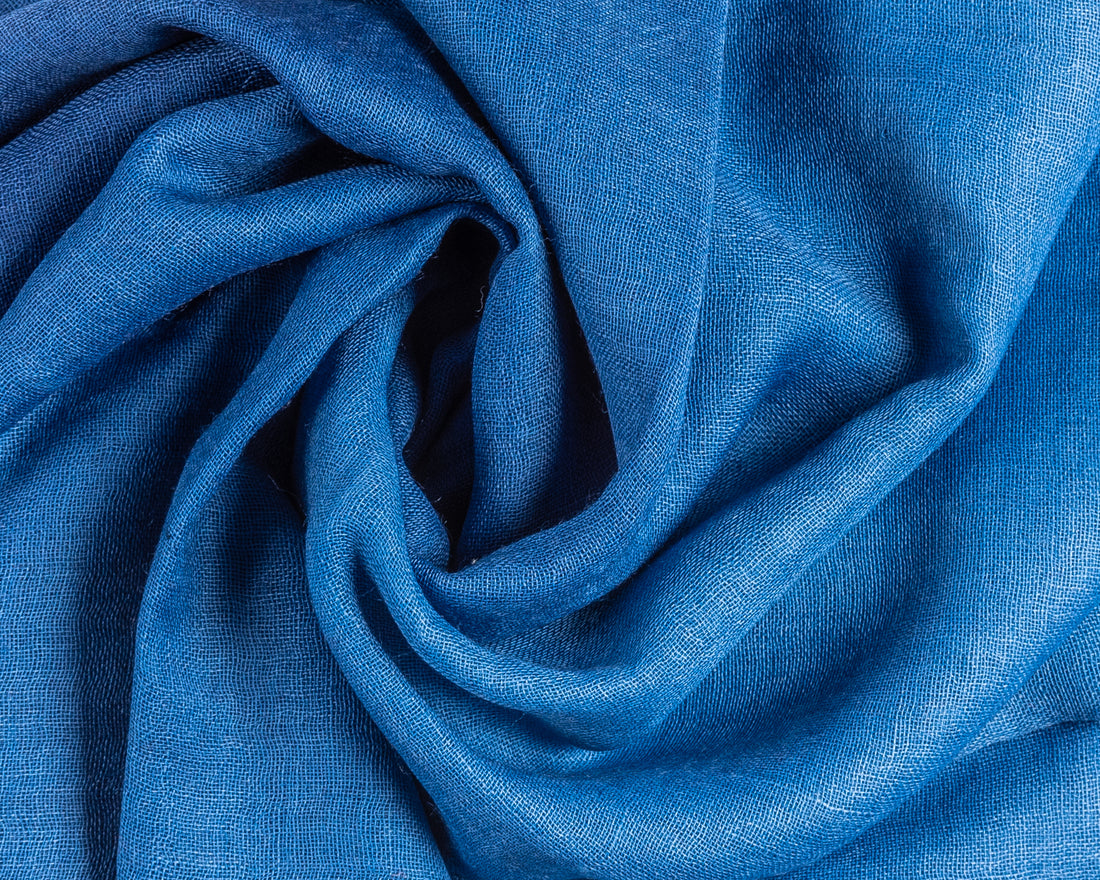Close-up of twisted blue linen fabric with soft folds and woven texture