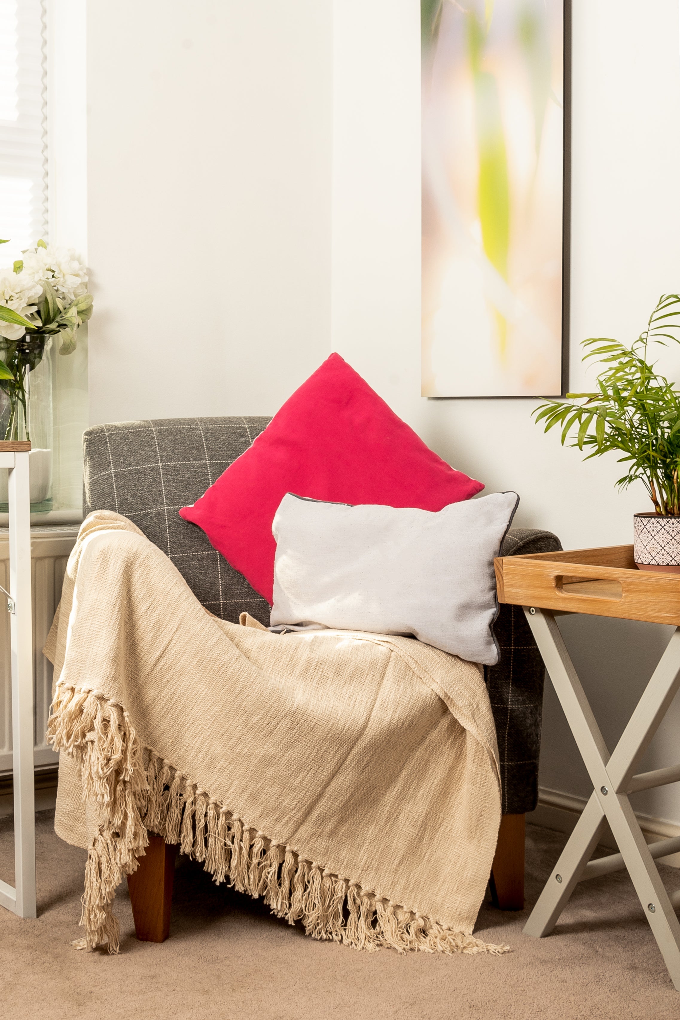 Gray armchair with pink and gray cushions and beige throw