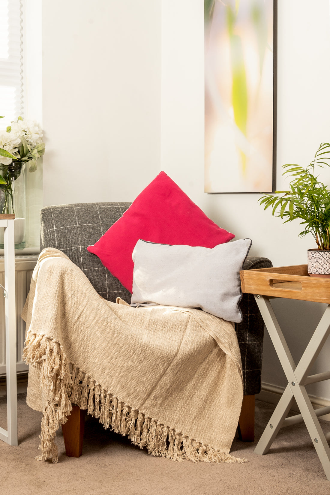 Gray armchair with pink and gray cushions and beige throw