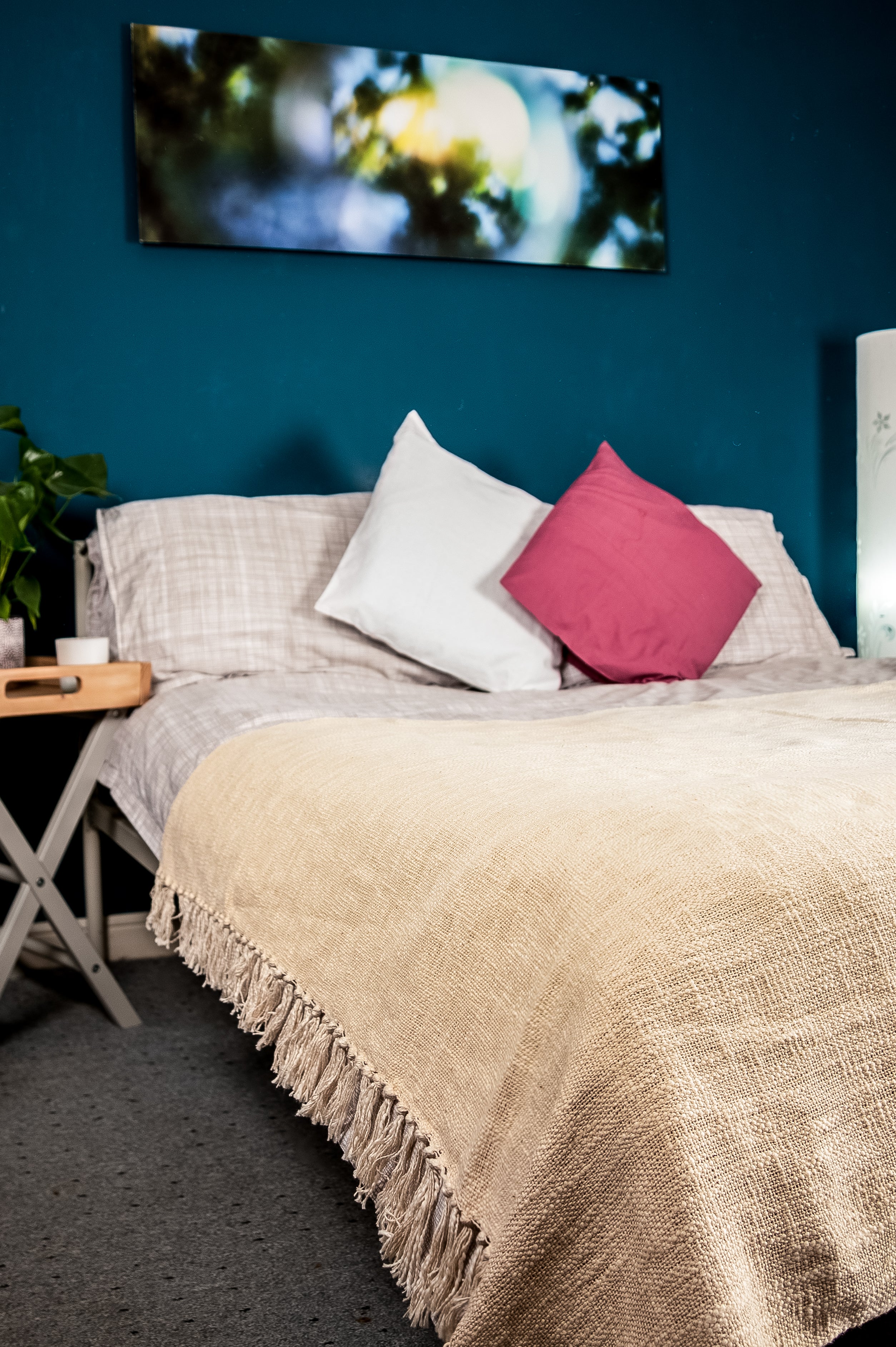 Cozy bedroom with beige fringed blanket and pink accent pillow