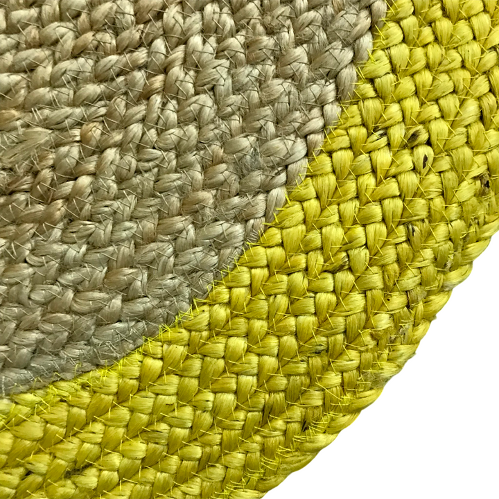 Close-up of a woven mat with beige and yellow patterns on a white background