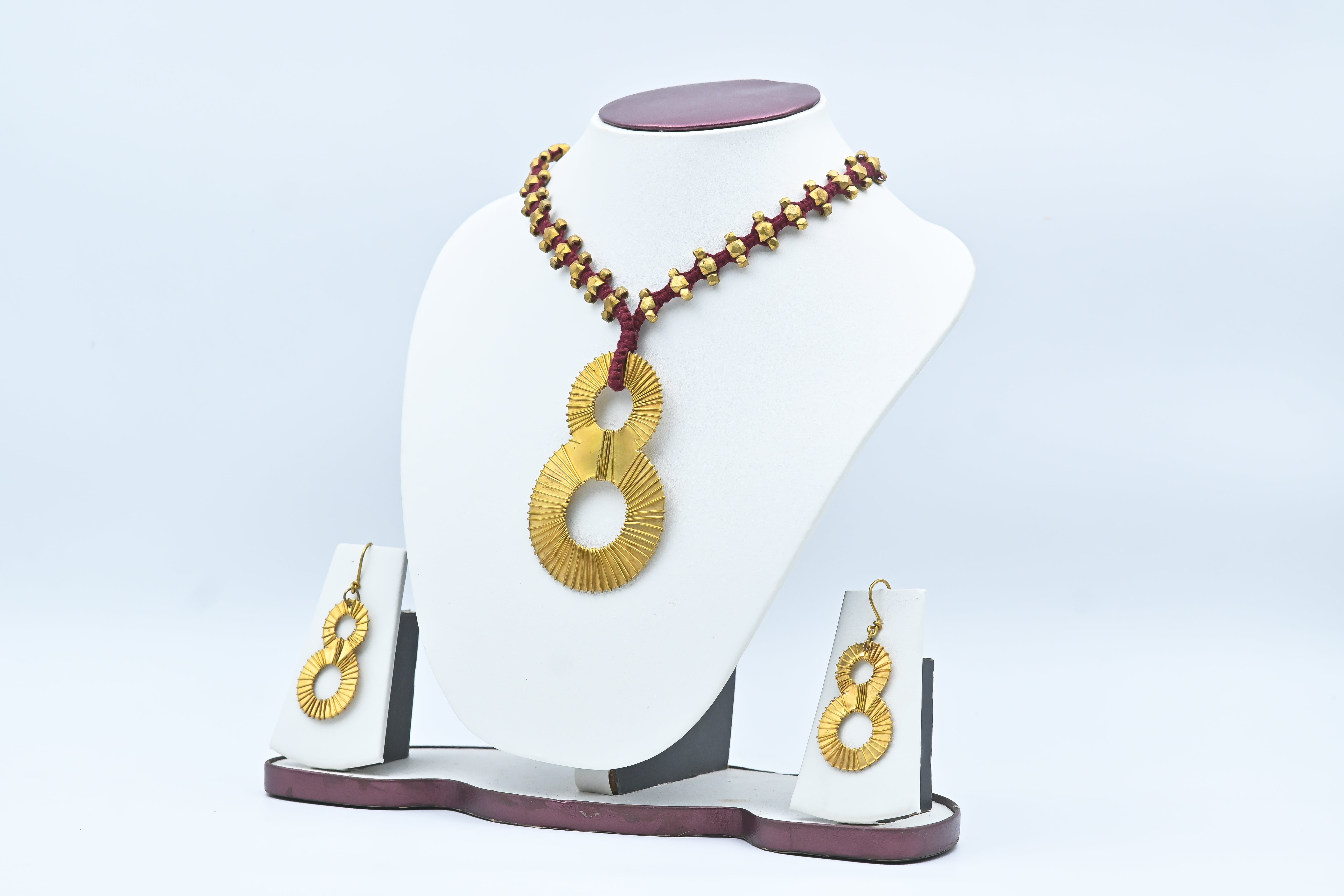 A woman sitting outdoors wearing a white dress and the Lucky Eight Tribal Necklace along with matching earrings.