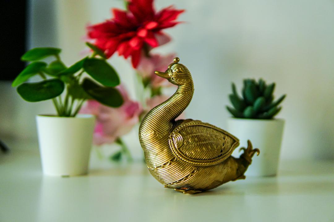 A Dhokra metal statue of an Indian swan with a gold hue.