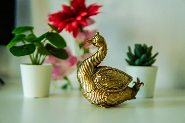 A Dhokra metal statue of an Indian swan with a gold hue.