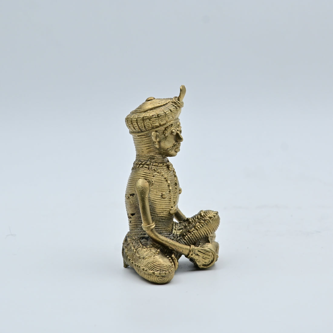 This item is a Dhokra (or Dokra) art brass statue depicting a seated tribal musician
