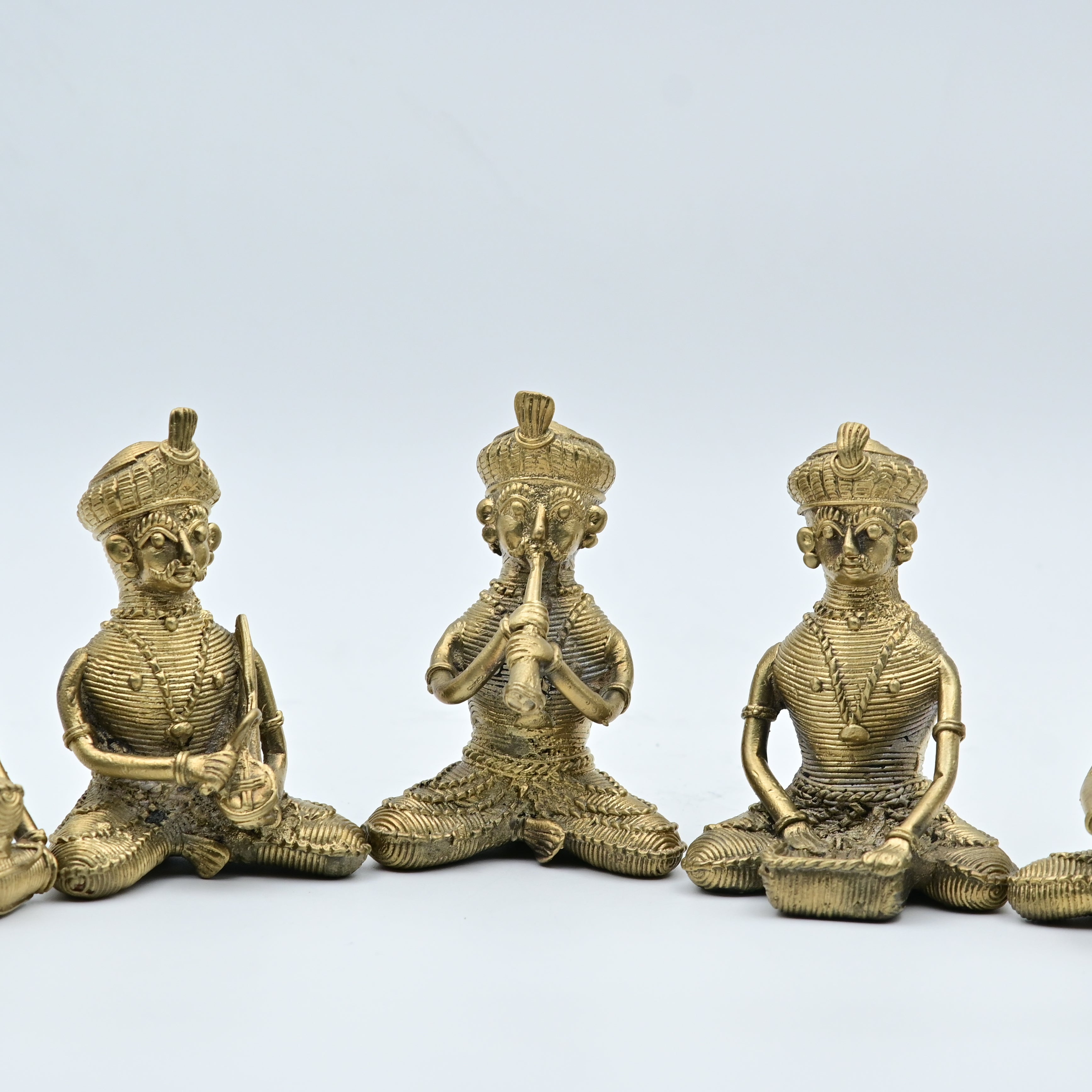 A set of five gold-colored statues of tribal musicians playing musical instruments, sitting in a row.